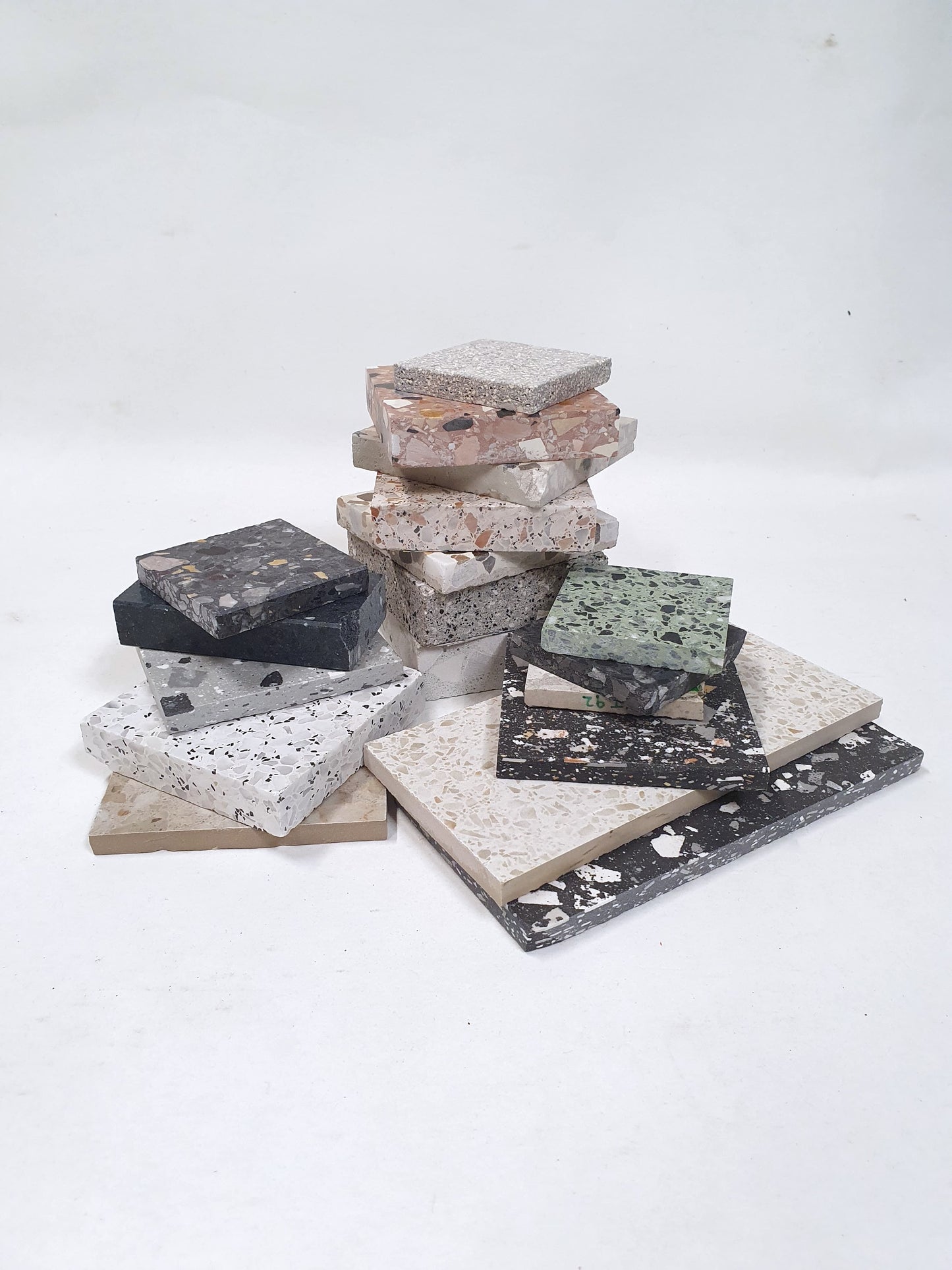 Terrazzo-style sample tiles are stacked on a white background