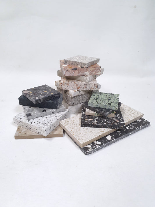 Terrazzo-style sample tiles are stacked on a white background