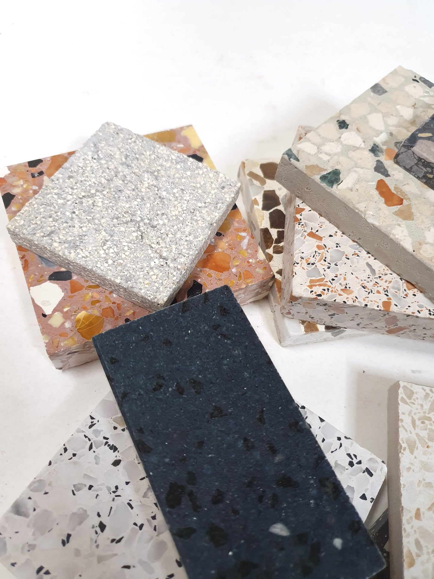 Square and rectangular sample tiles are layered on a white surface