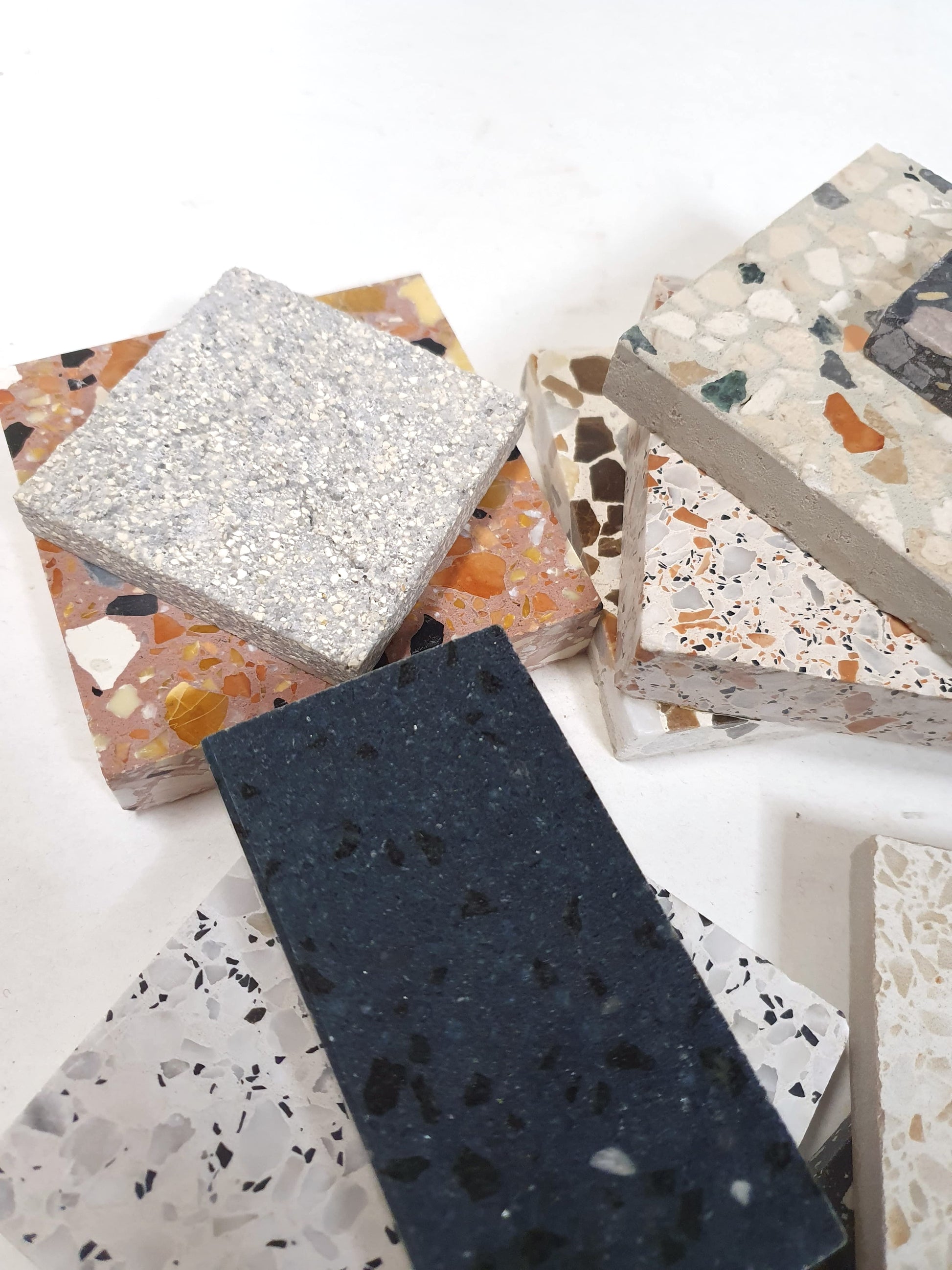 Square and rectangular sample tiles are layered on a white surface