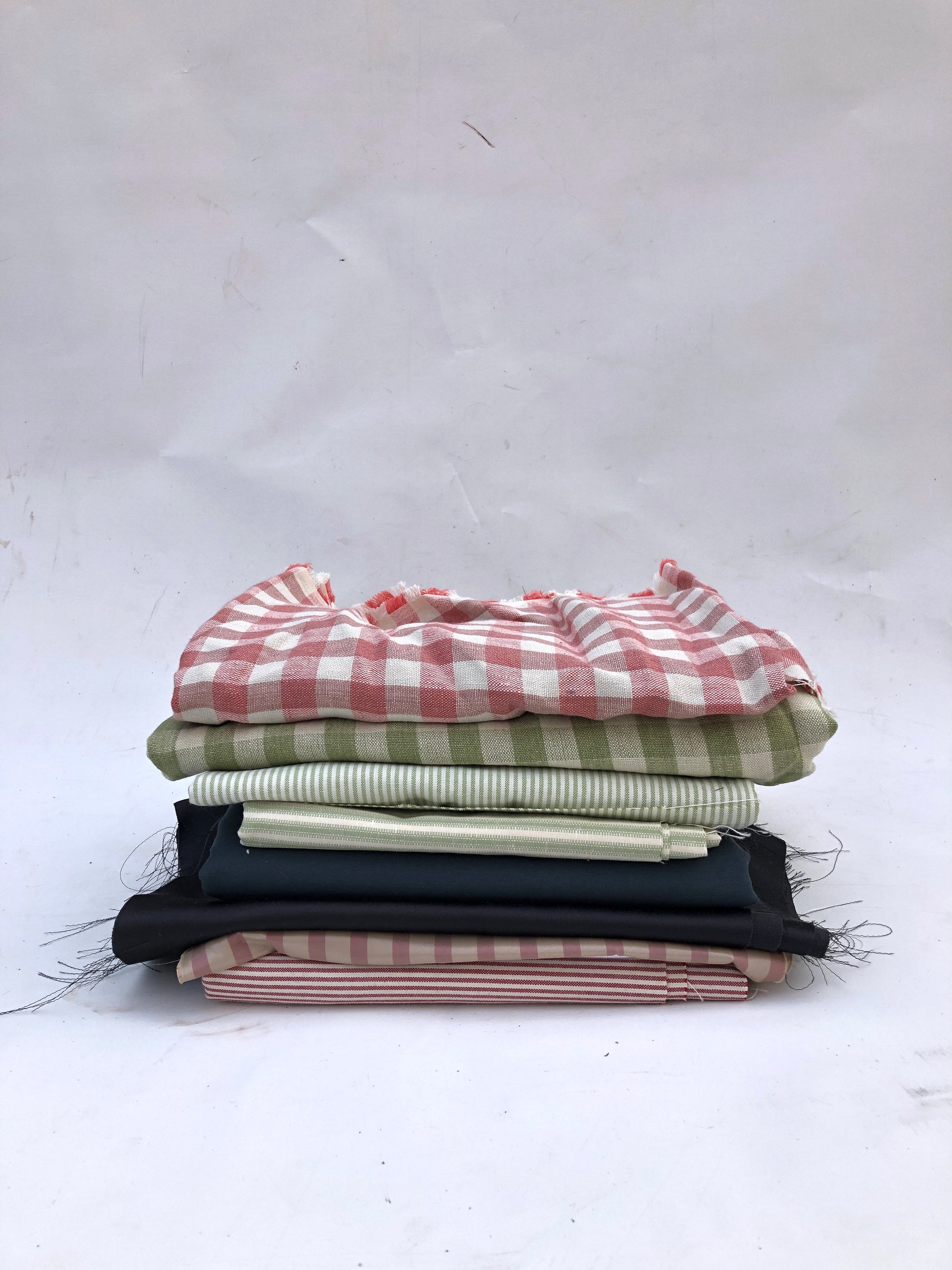 Folded fabric pieces are stacked in a mixed pile on white