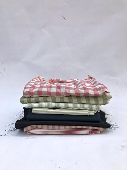 Folded fabric pieces are stacked in a mixed pile on white