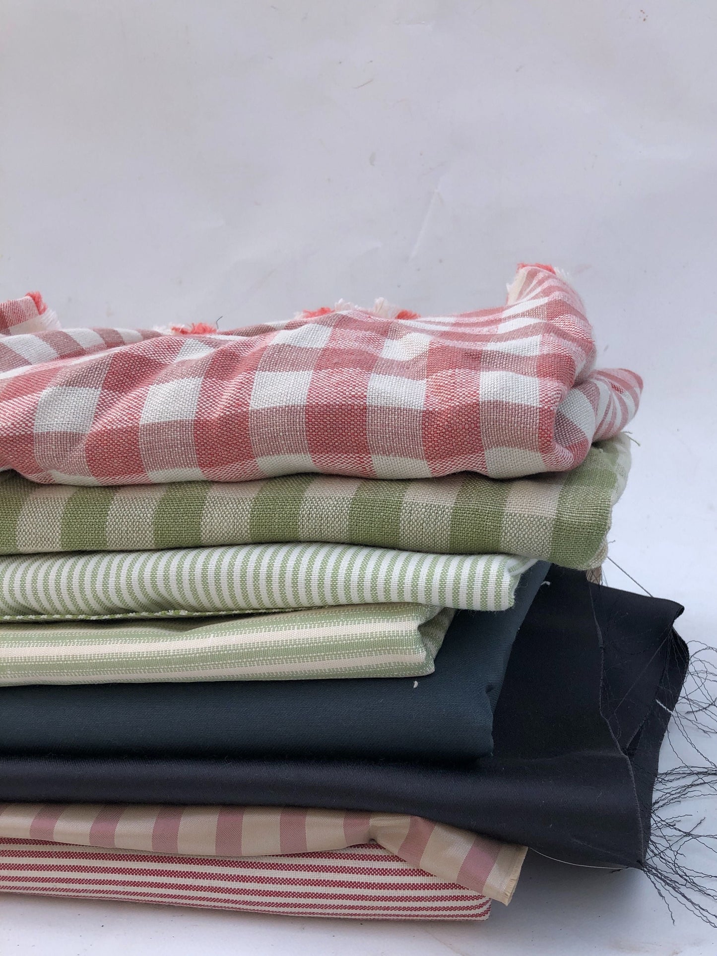 Folded fabrics are stacked in detail with striped and checked patterns