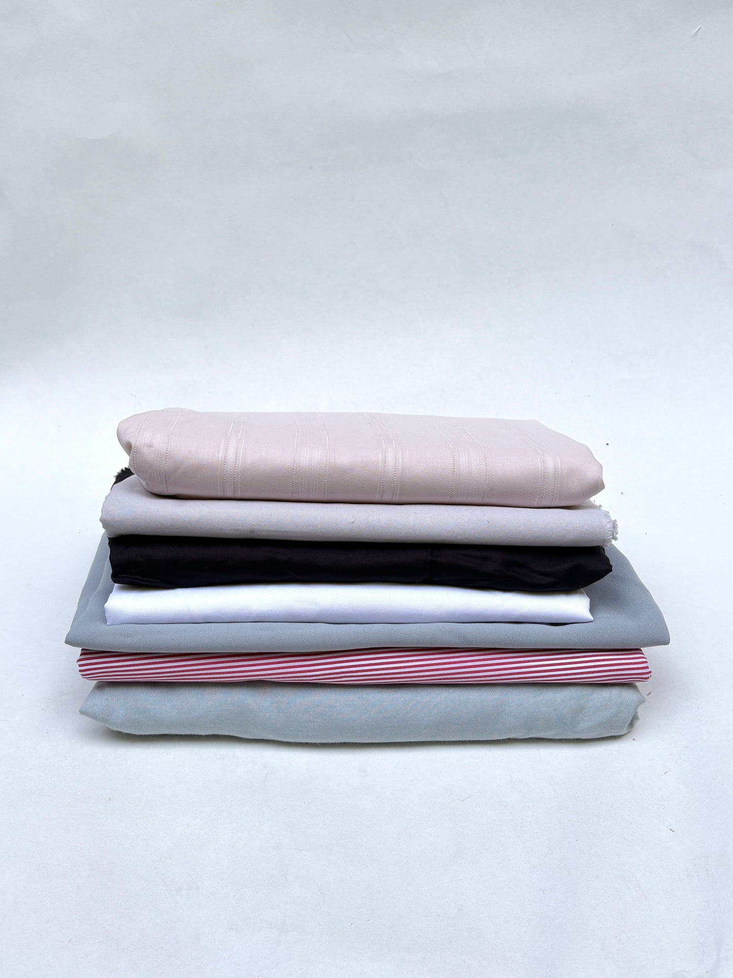 Folded fabric pieces are stacked on a white background