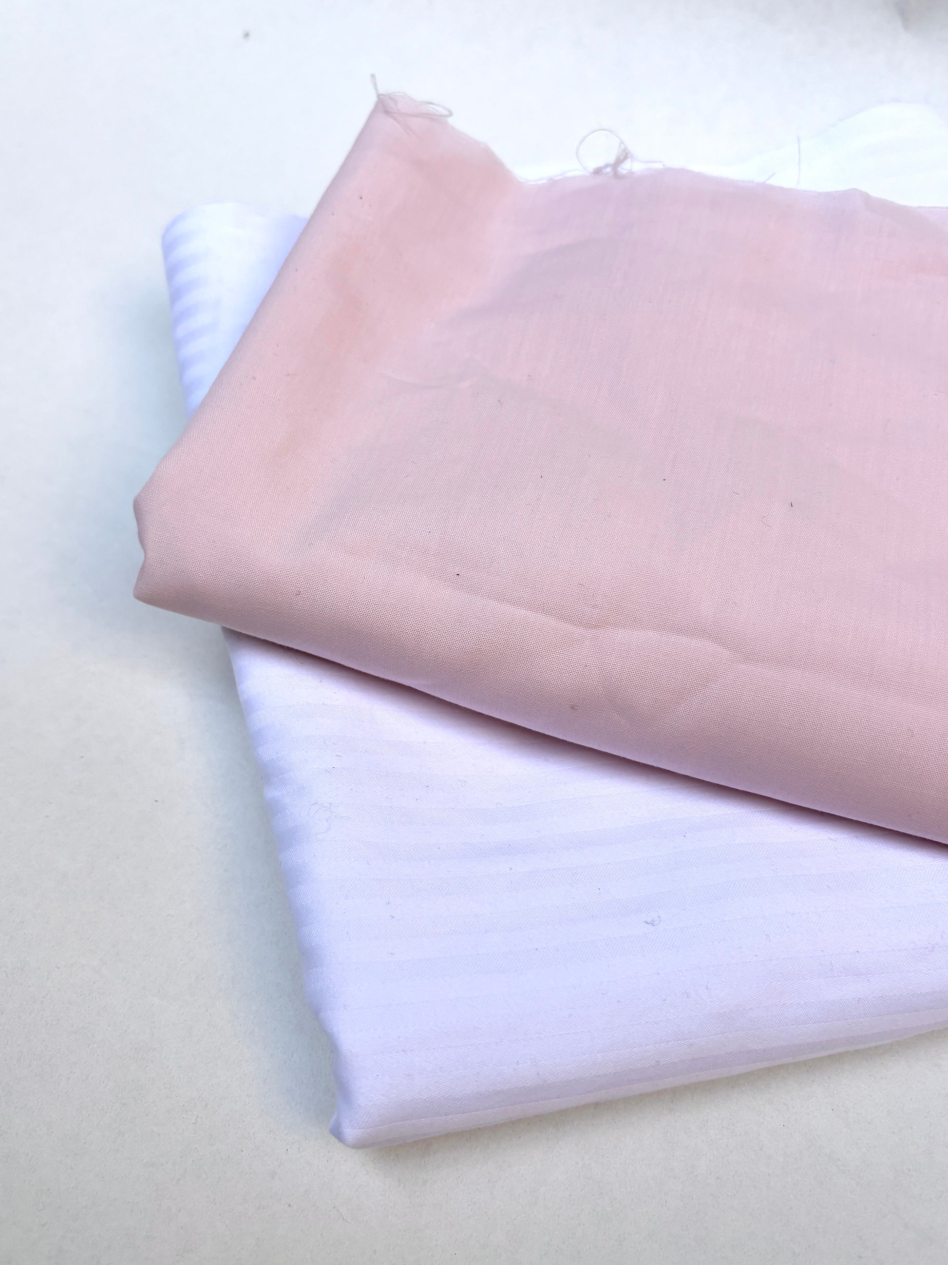 A stack of folded pink and purple textiles sits on a white surface