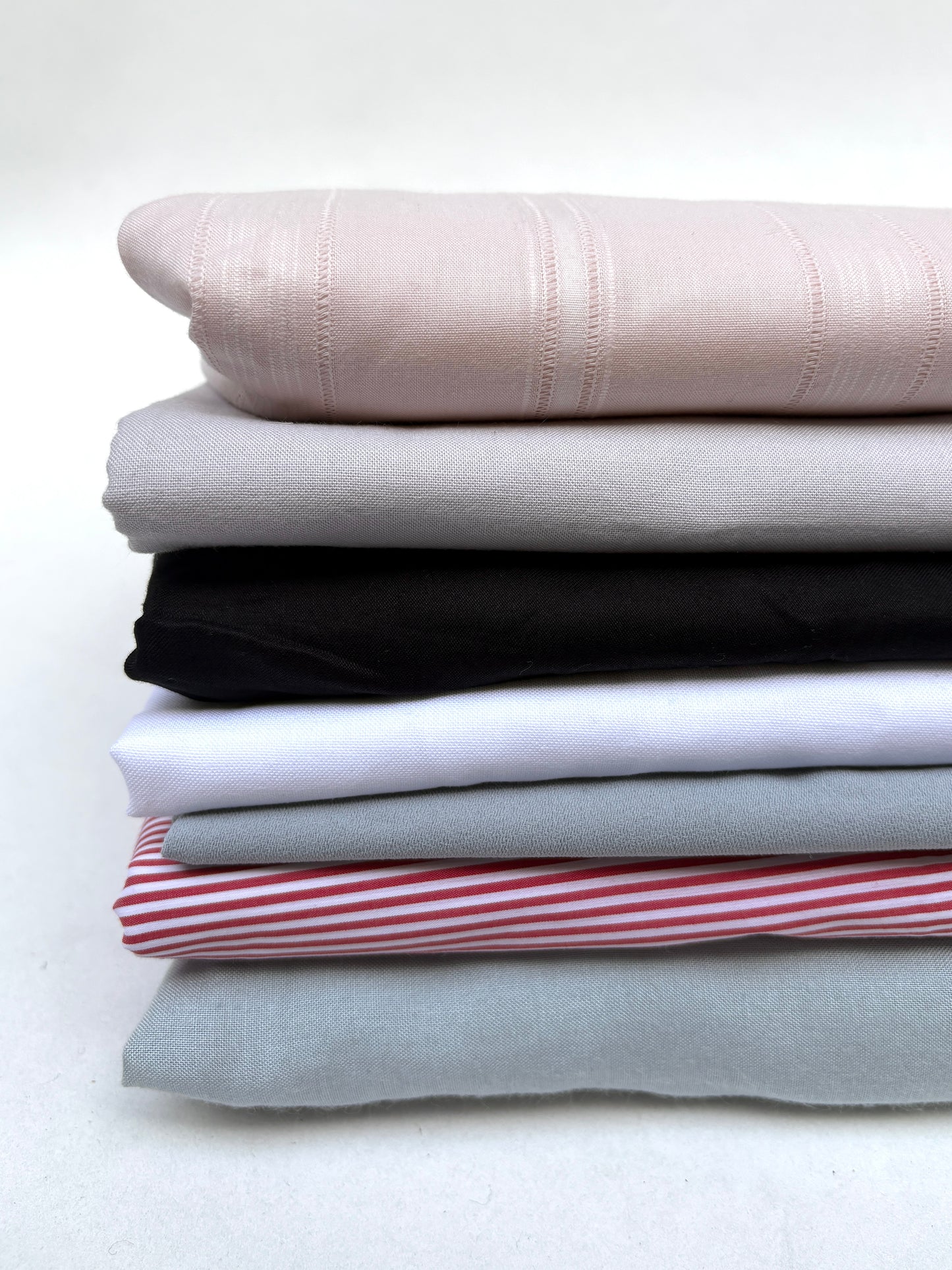 Folded fabric pieces in mixed colours are shown together