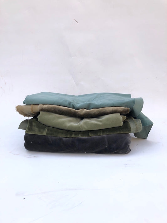 Velvet fabric pieces are stacked in a soft folded pile on white
