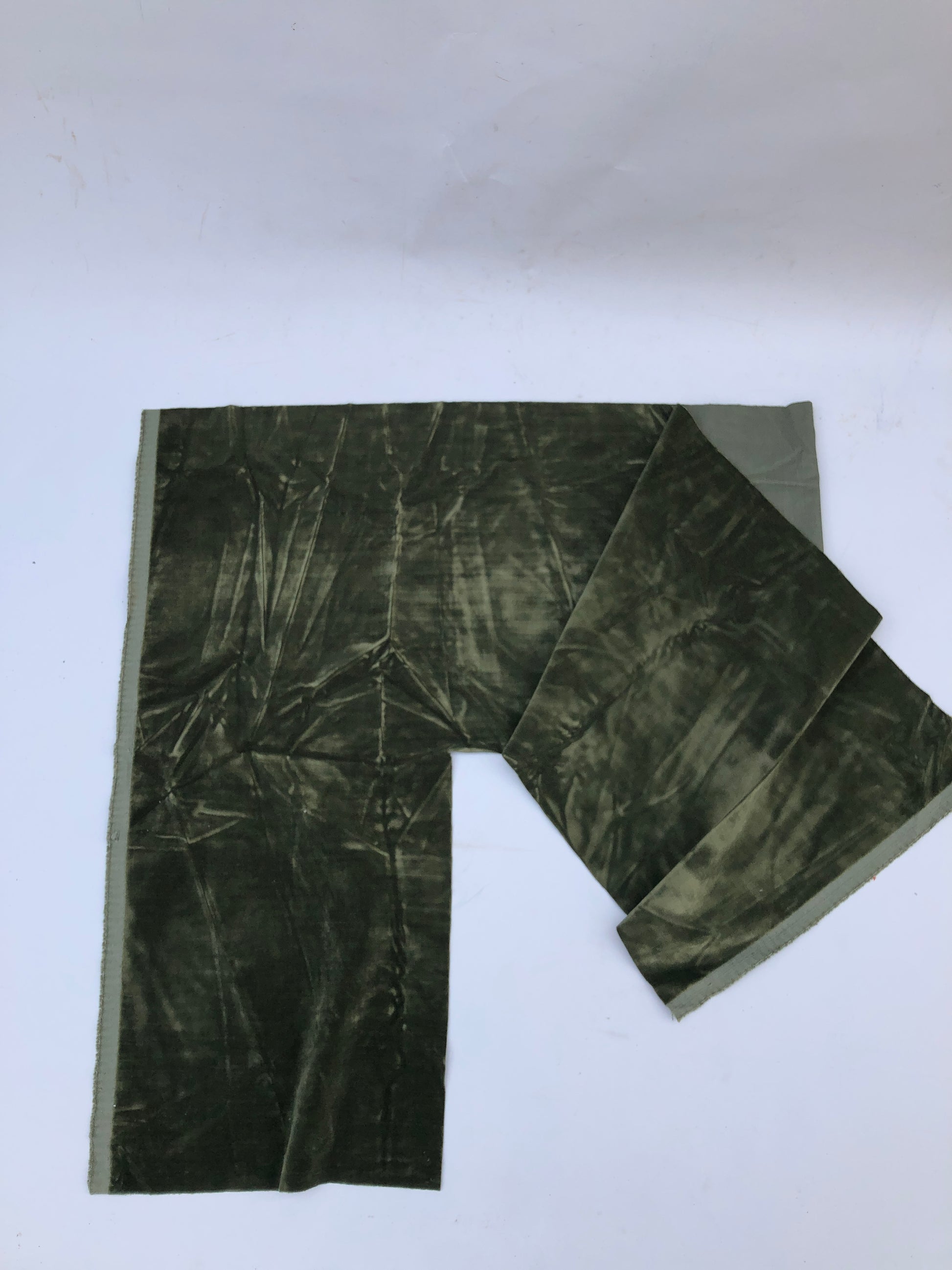 Green velvet fabric is shown in detail with visible surface creases