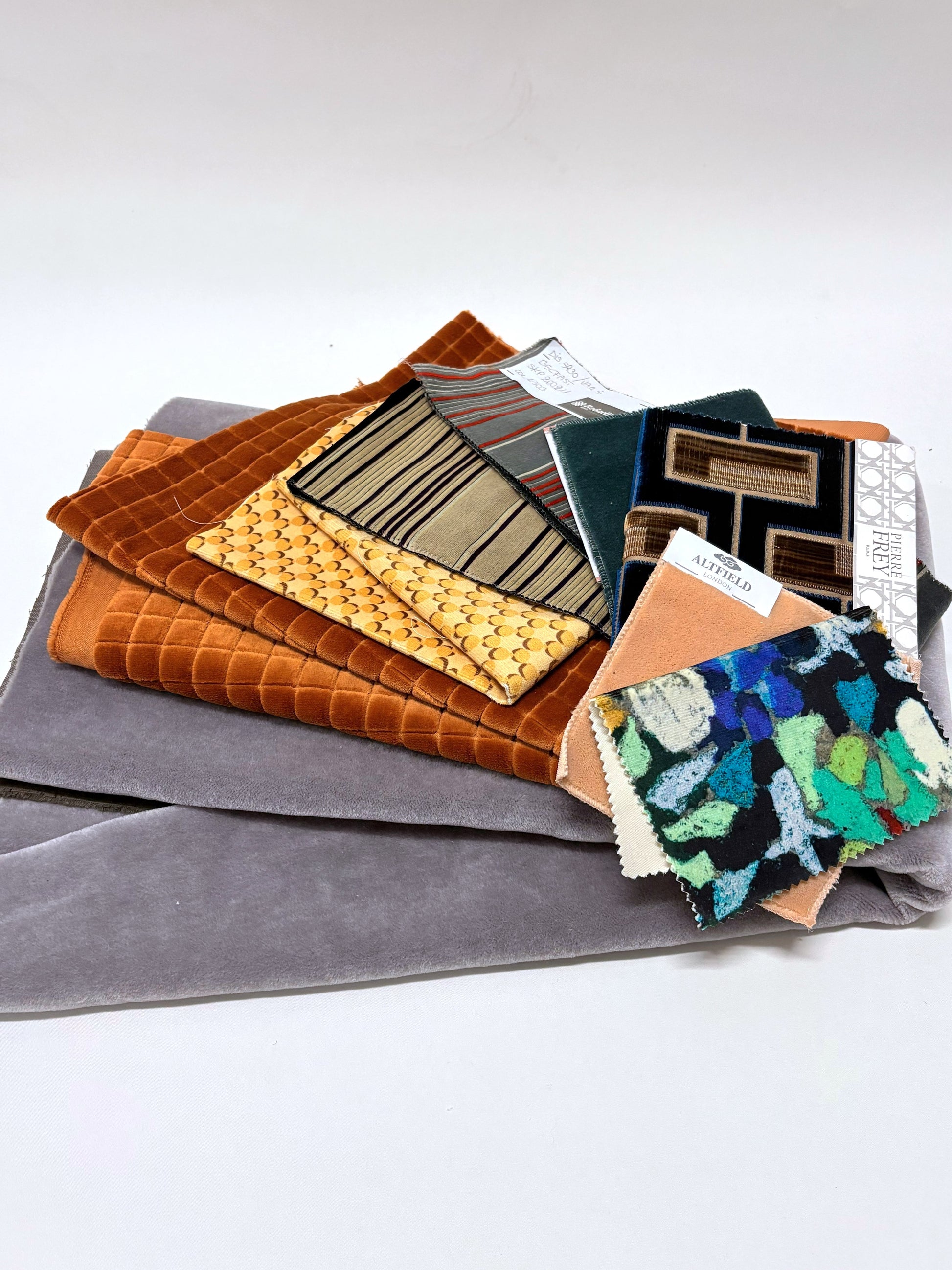 Layered mixed fabric pieces with sample swatches in assorted colours and textures.