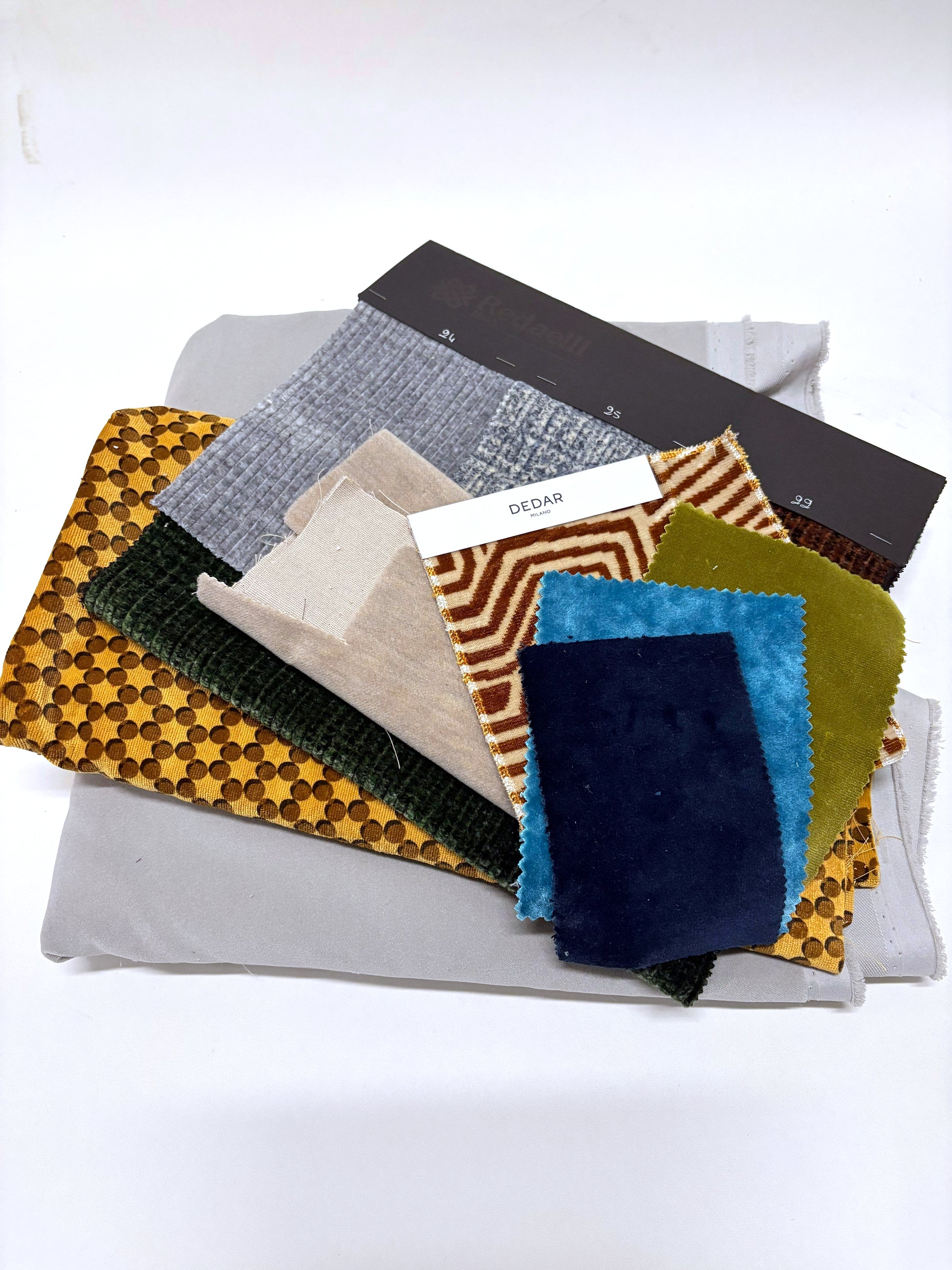 Mixed fabric pieces and sample swatches layered in assorted colours and textures.