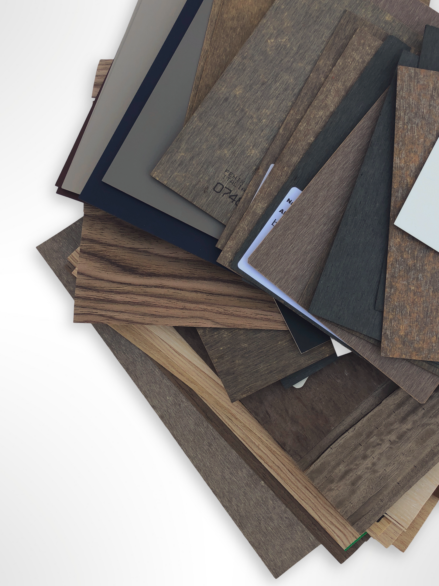 Mixed wood-effect sample boards are stacked on a white background