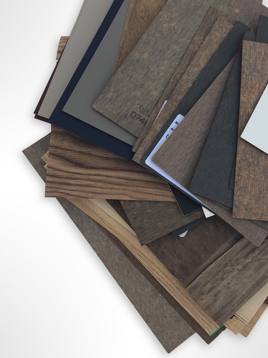 Mixed wood-effect sample boards are stacked on a white background