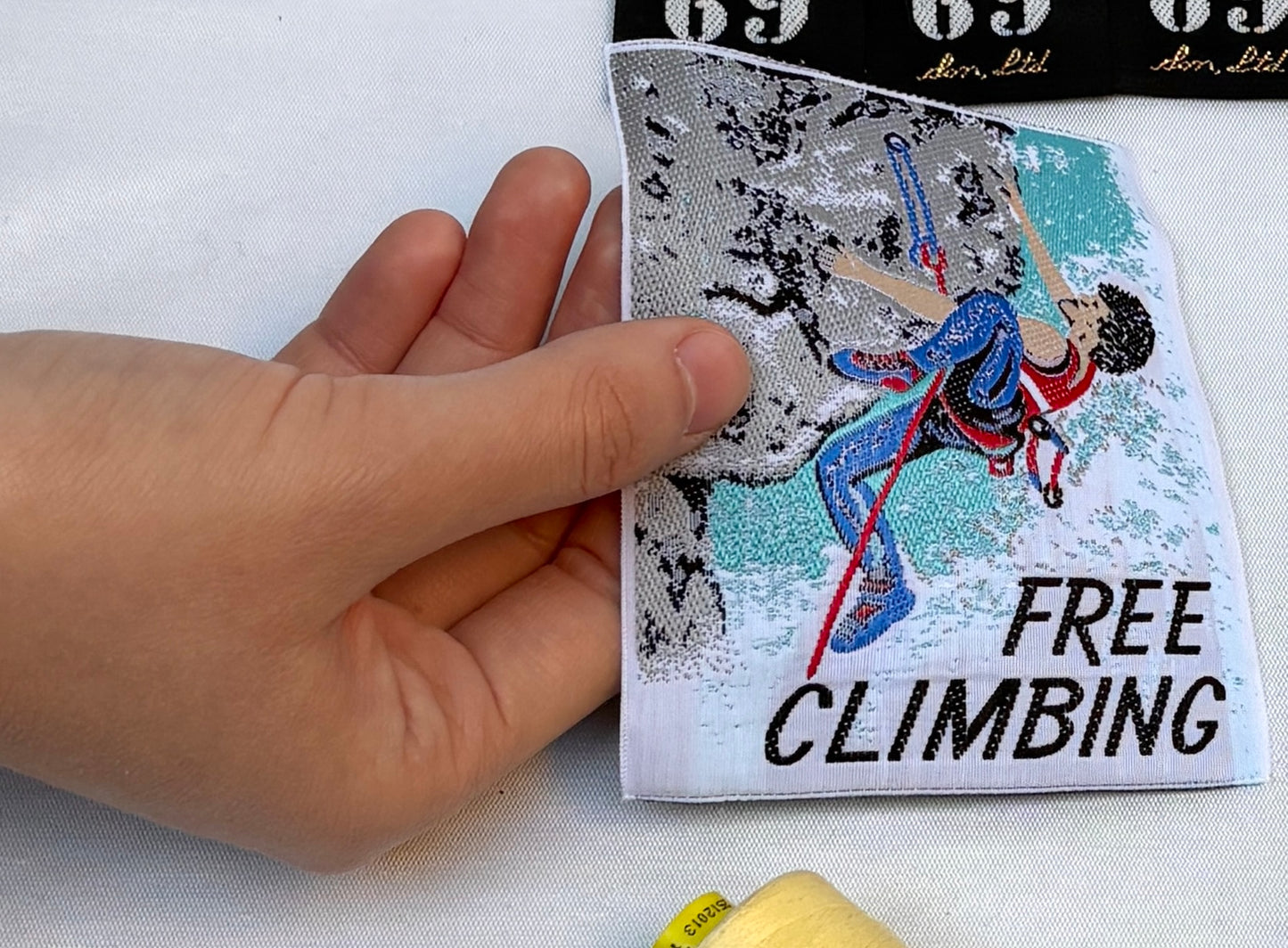 A hand holding the vintage free climbing embellished badge against a neutral background.
