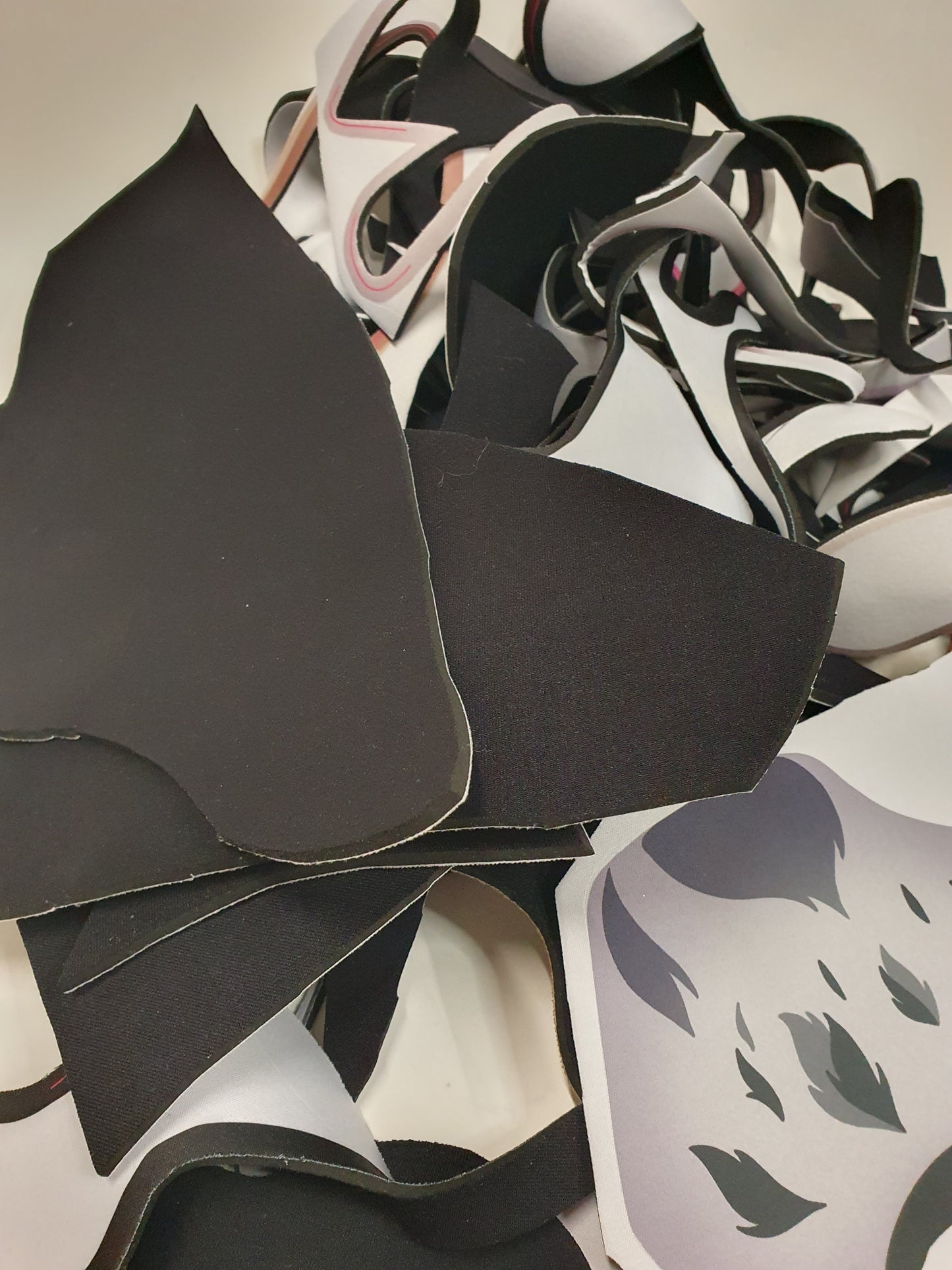 Curved and flat material scraps are arranged on a white surface