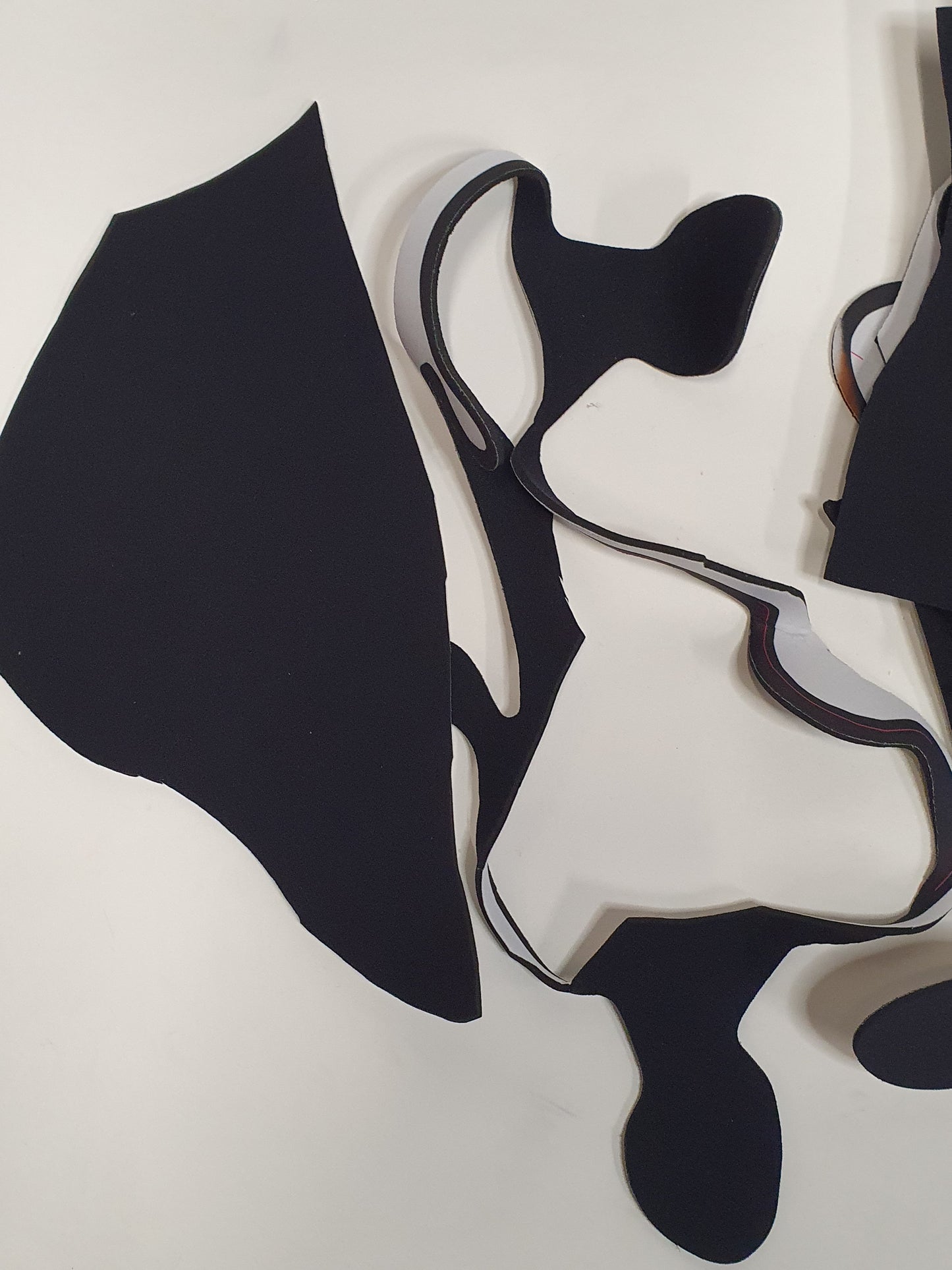 Black material offcuts are piled on a white background