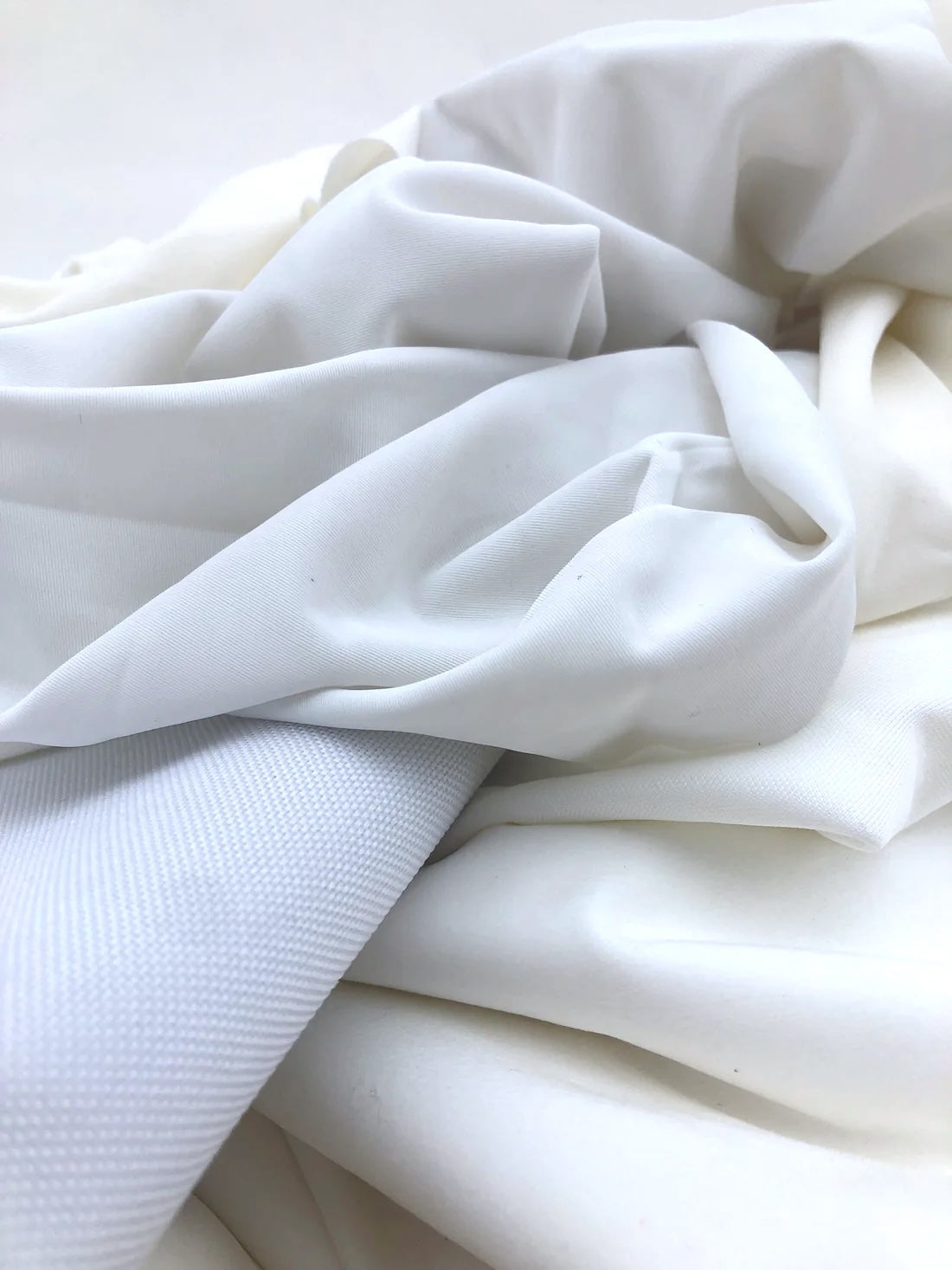 White fabric is draped in soft folds on a white background