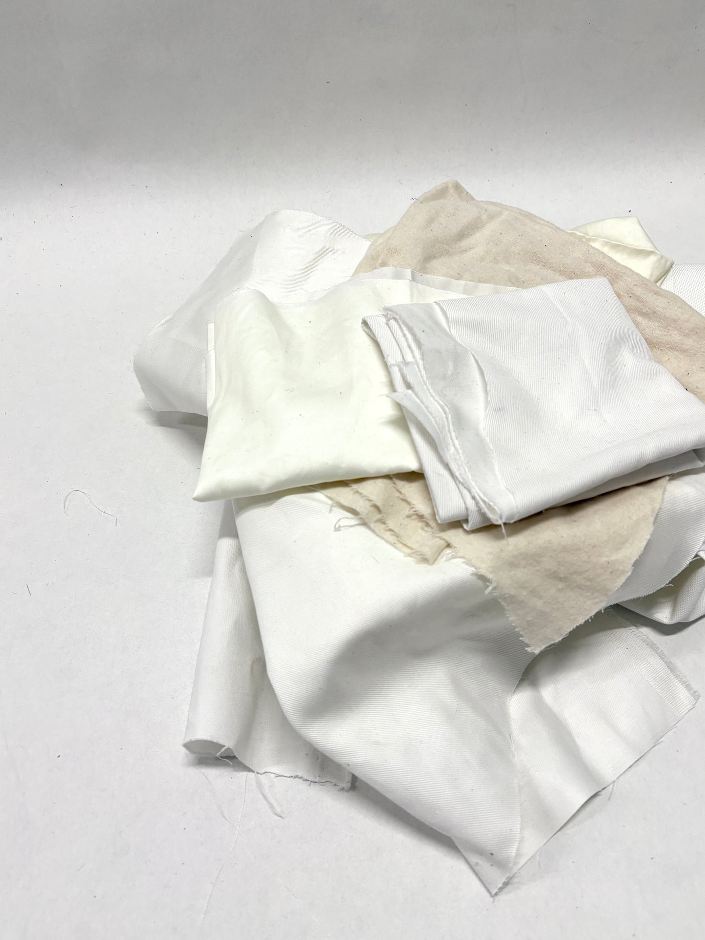 White fabric pieces are stacked in a loose pile on white