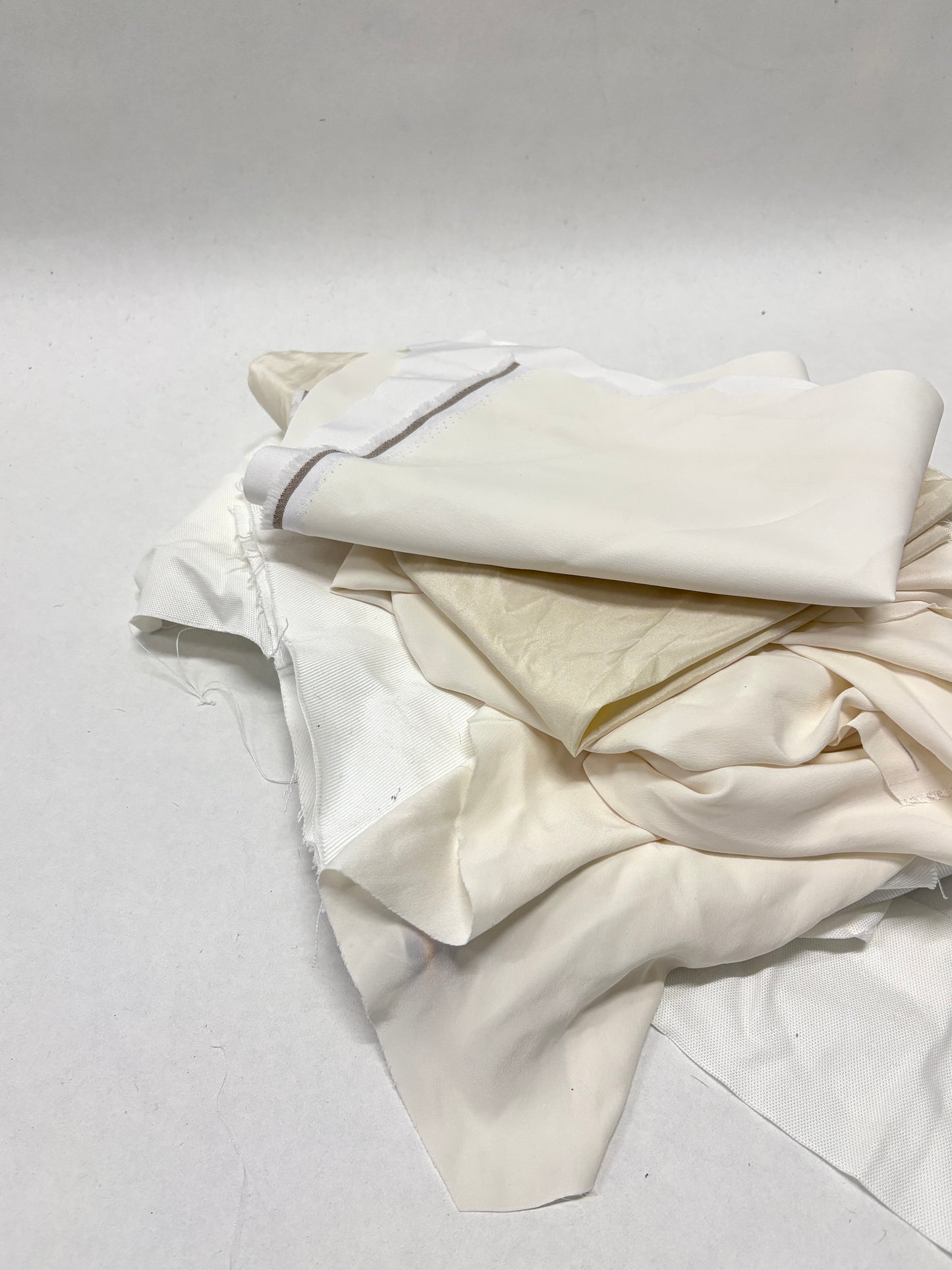 Folded white fabric offcuts are arranged on a white surface