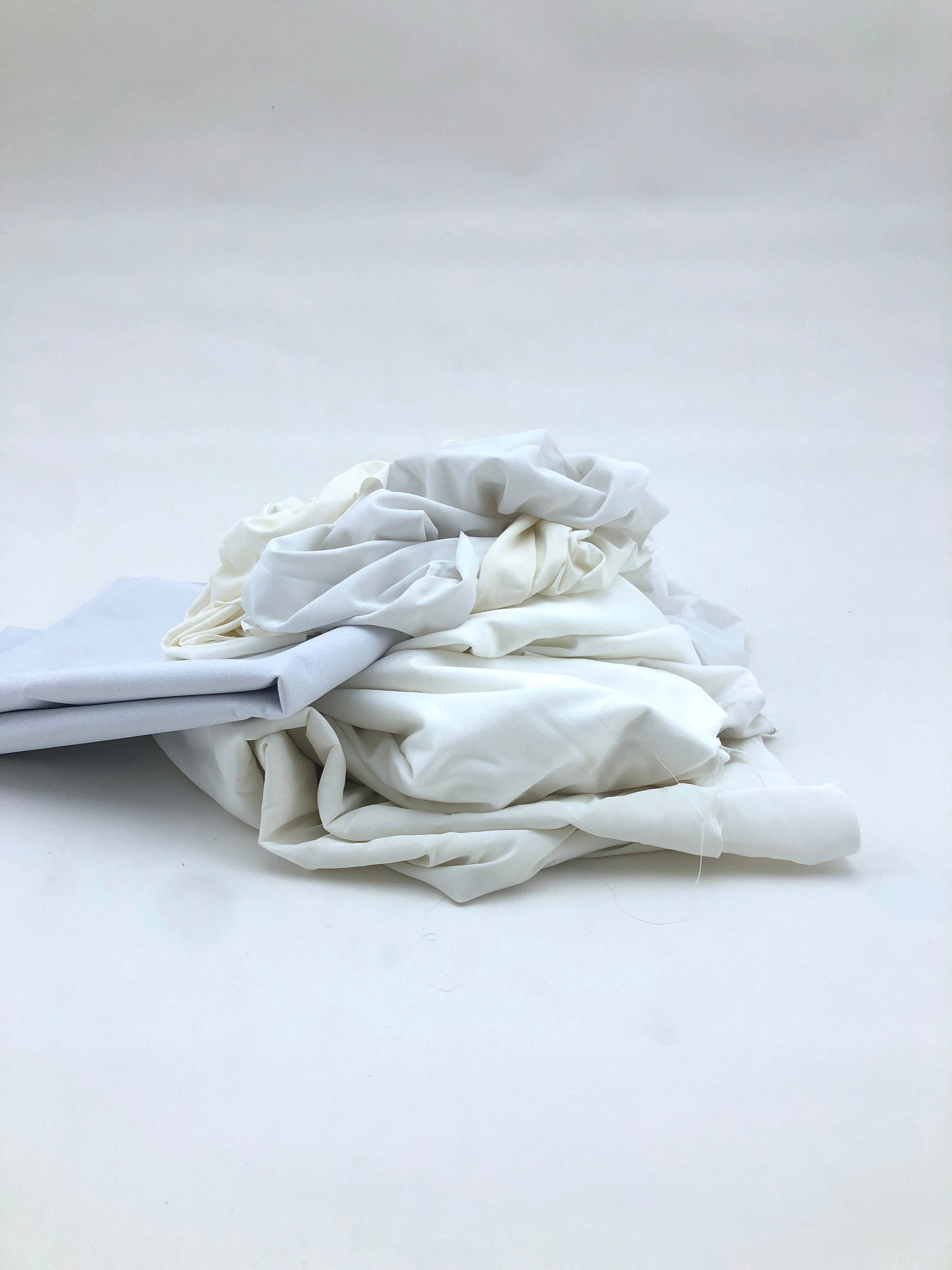 White fabric is gathered into a soft bundle on a white background