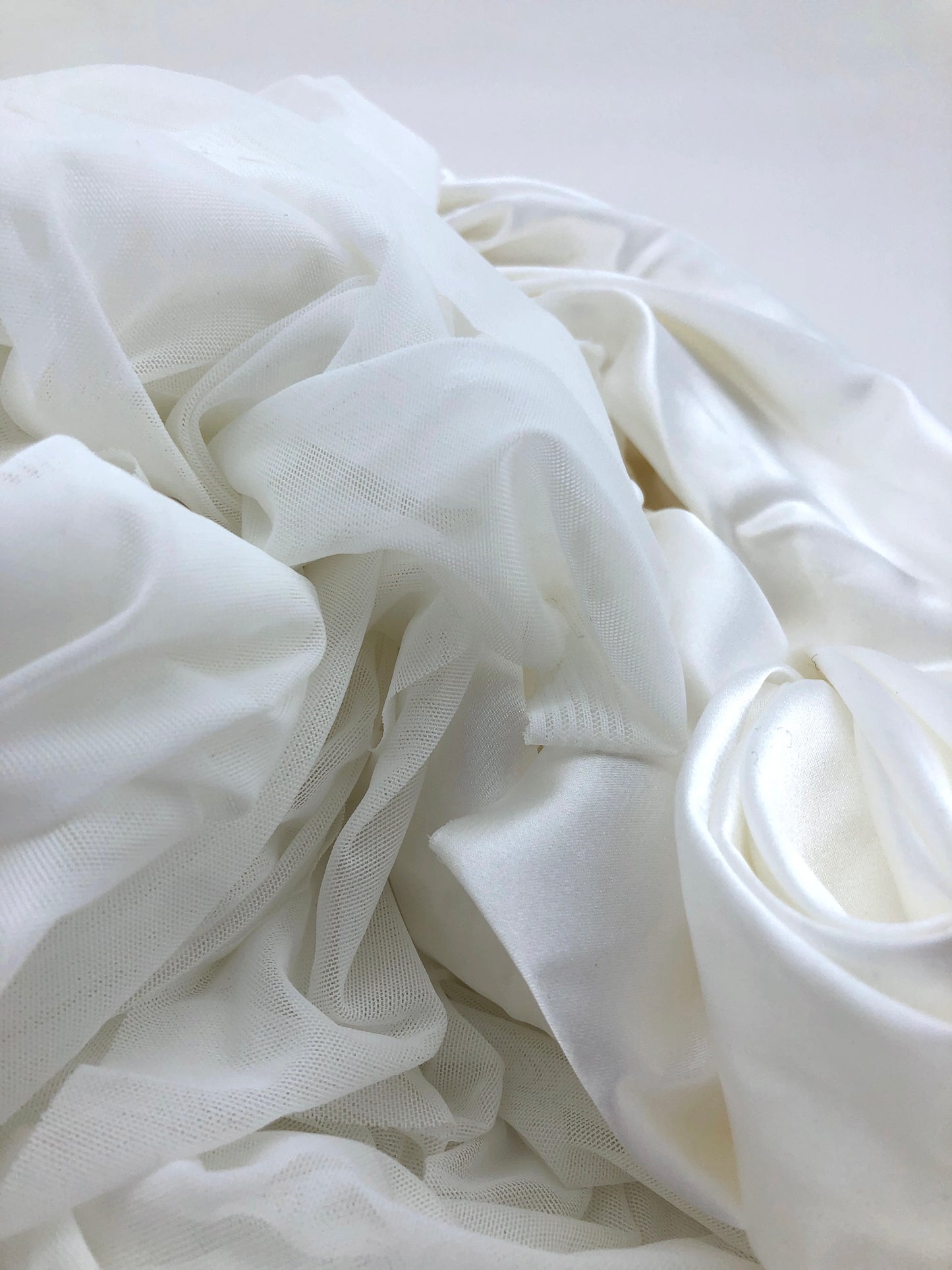 White fabric is piled in soft folds on a white background