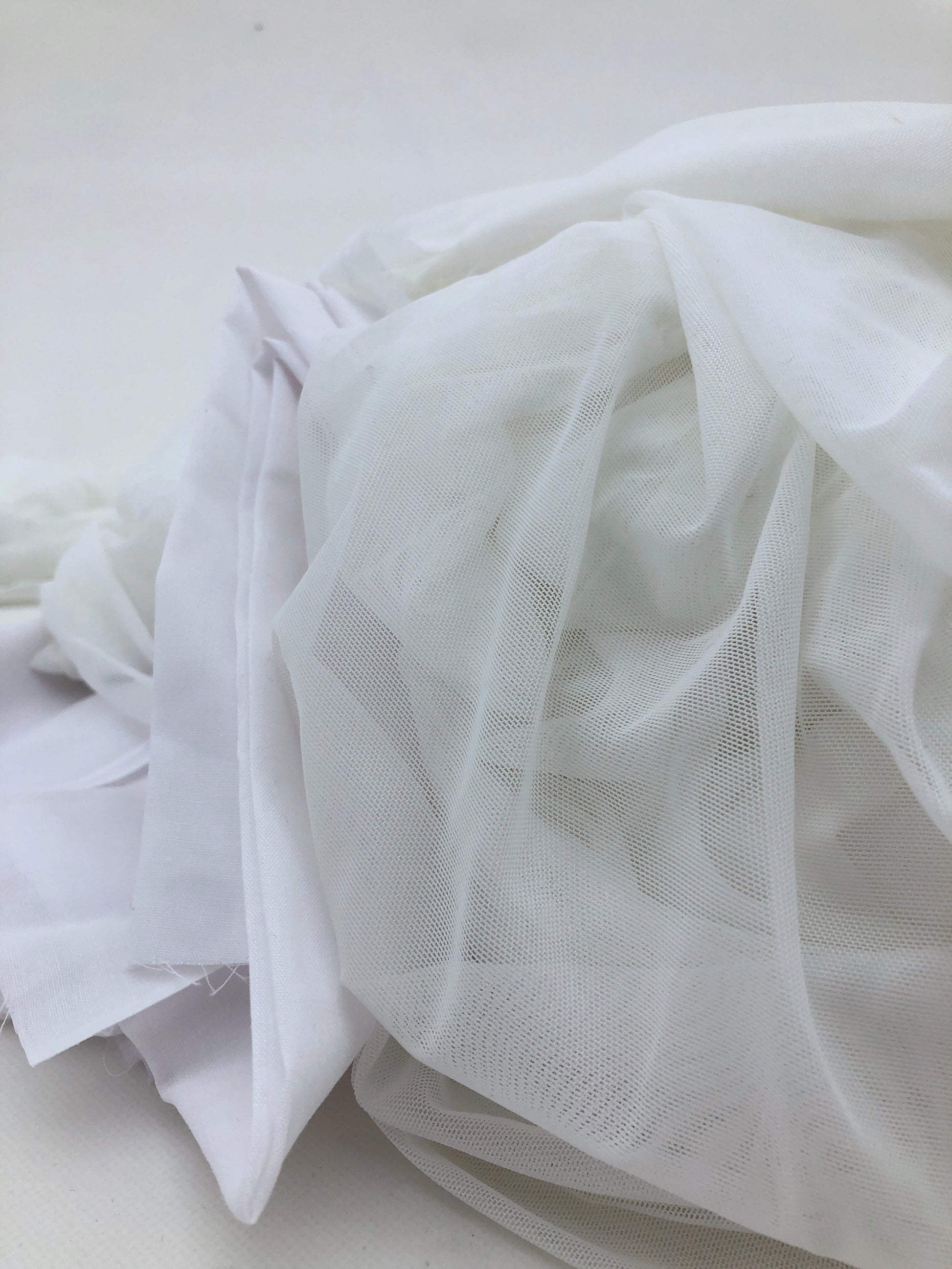 Sheer white fabric is gathered loosely with visible soft texture