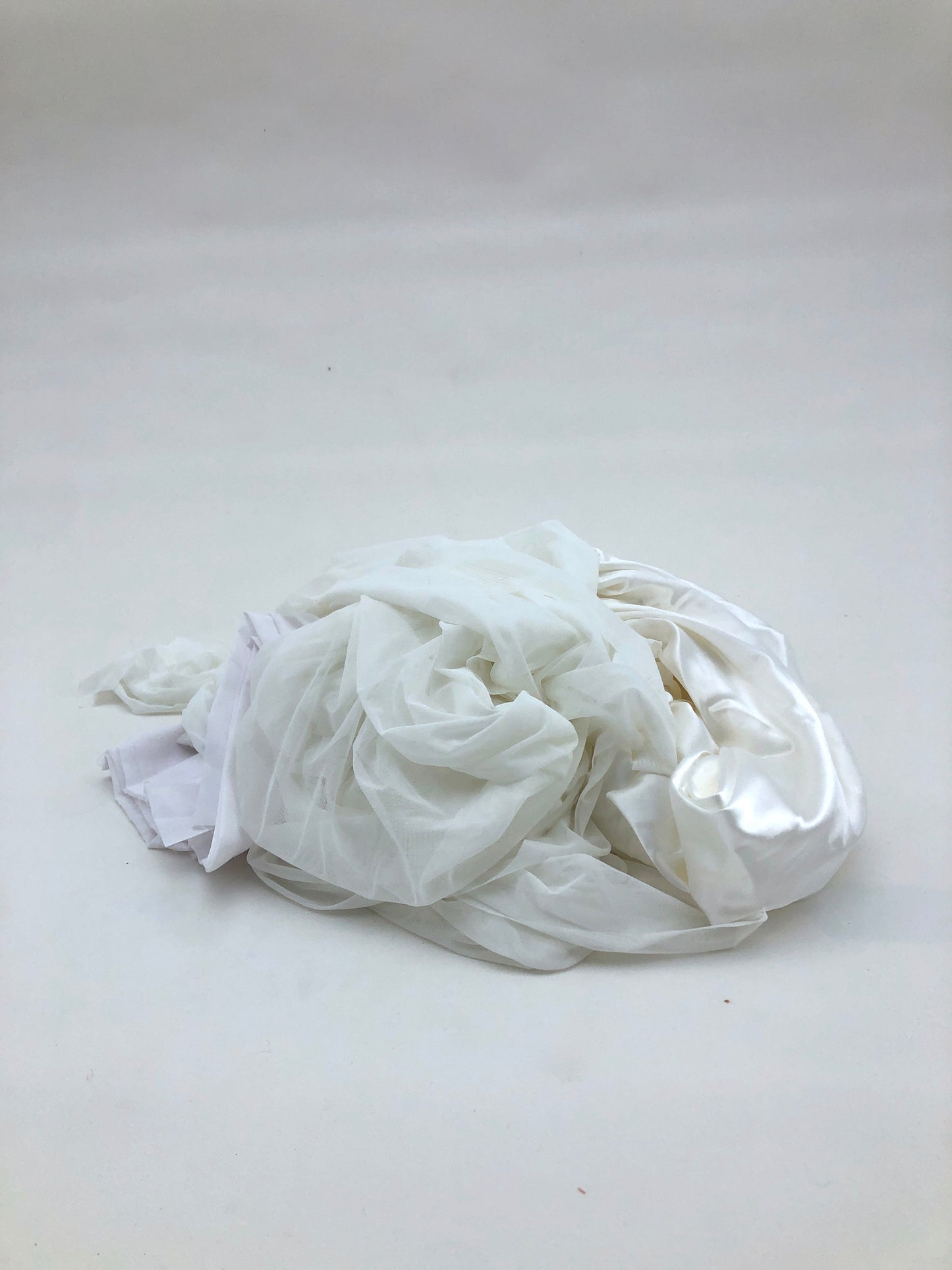 A small bundle of white fabric rests on a white background 