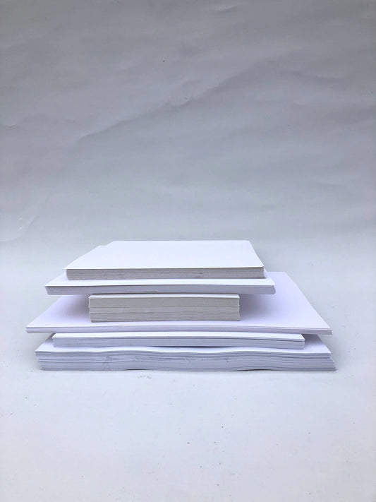 White paper sheets are stacked in mixed sizes on white.