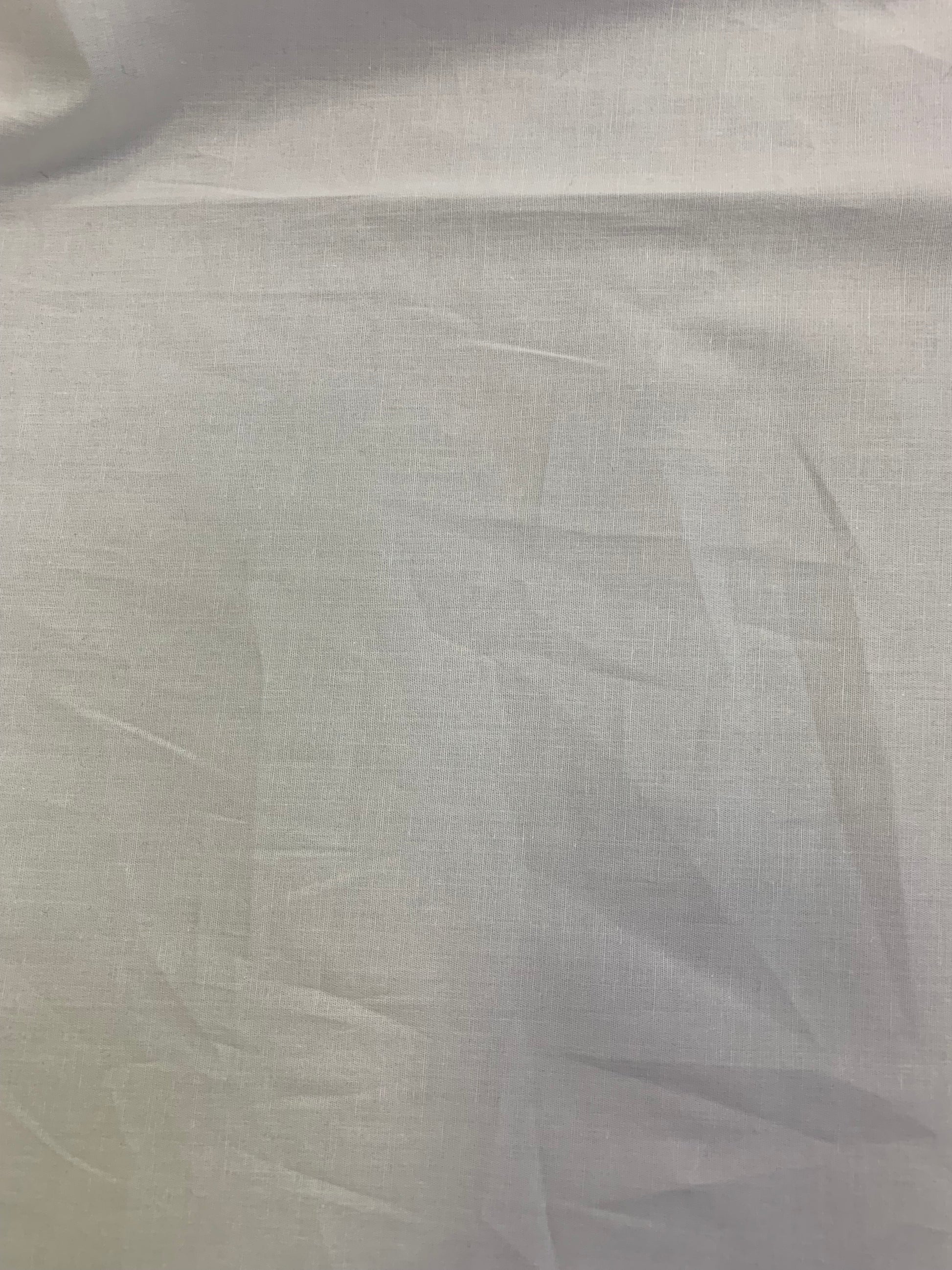 Light white cotton fabric has subtle creases and texture