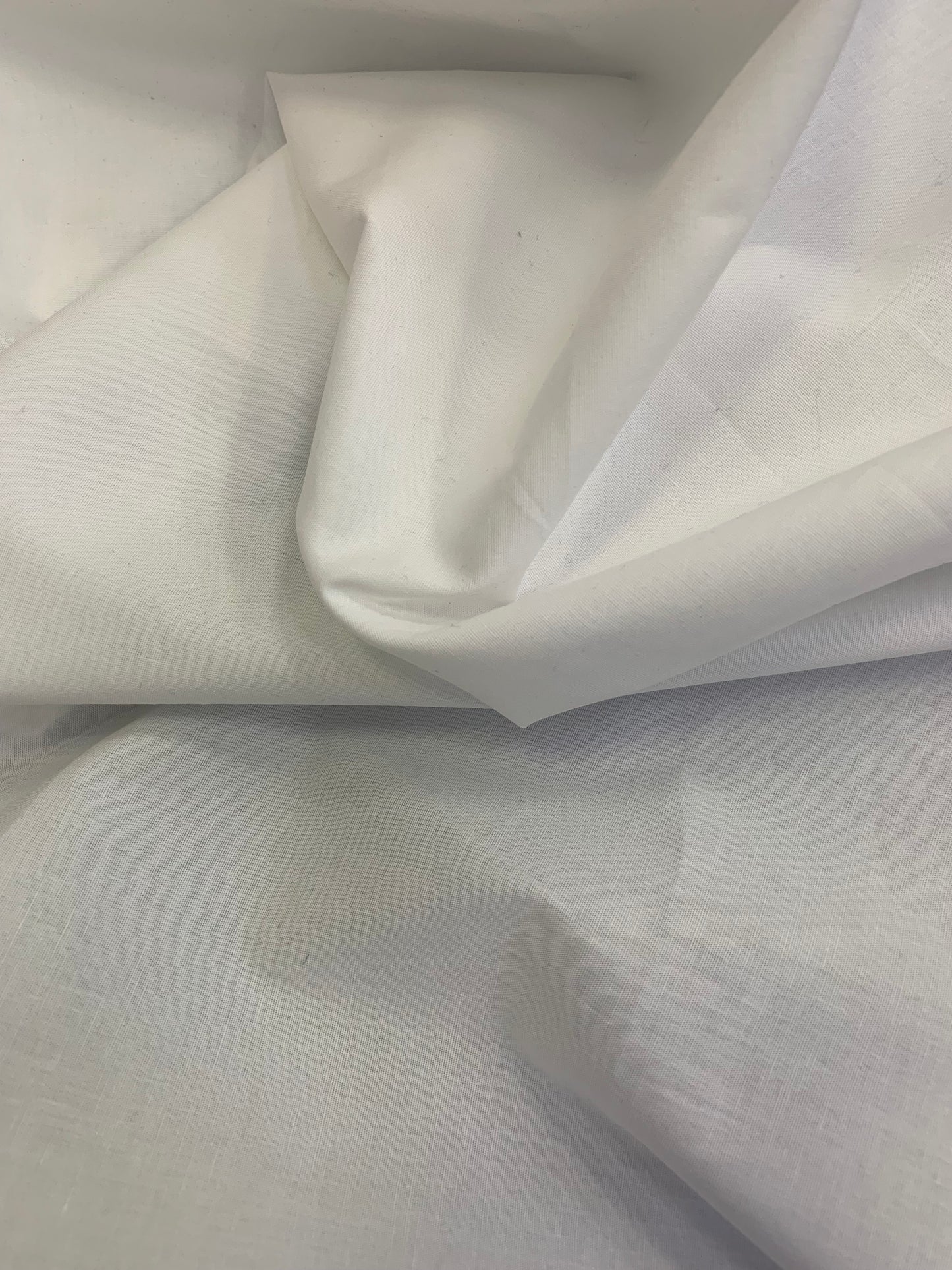 Plain white fabric is shown close-up with soft folds