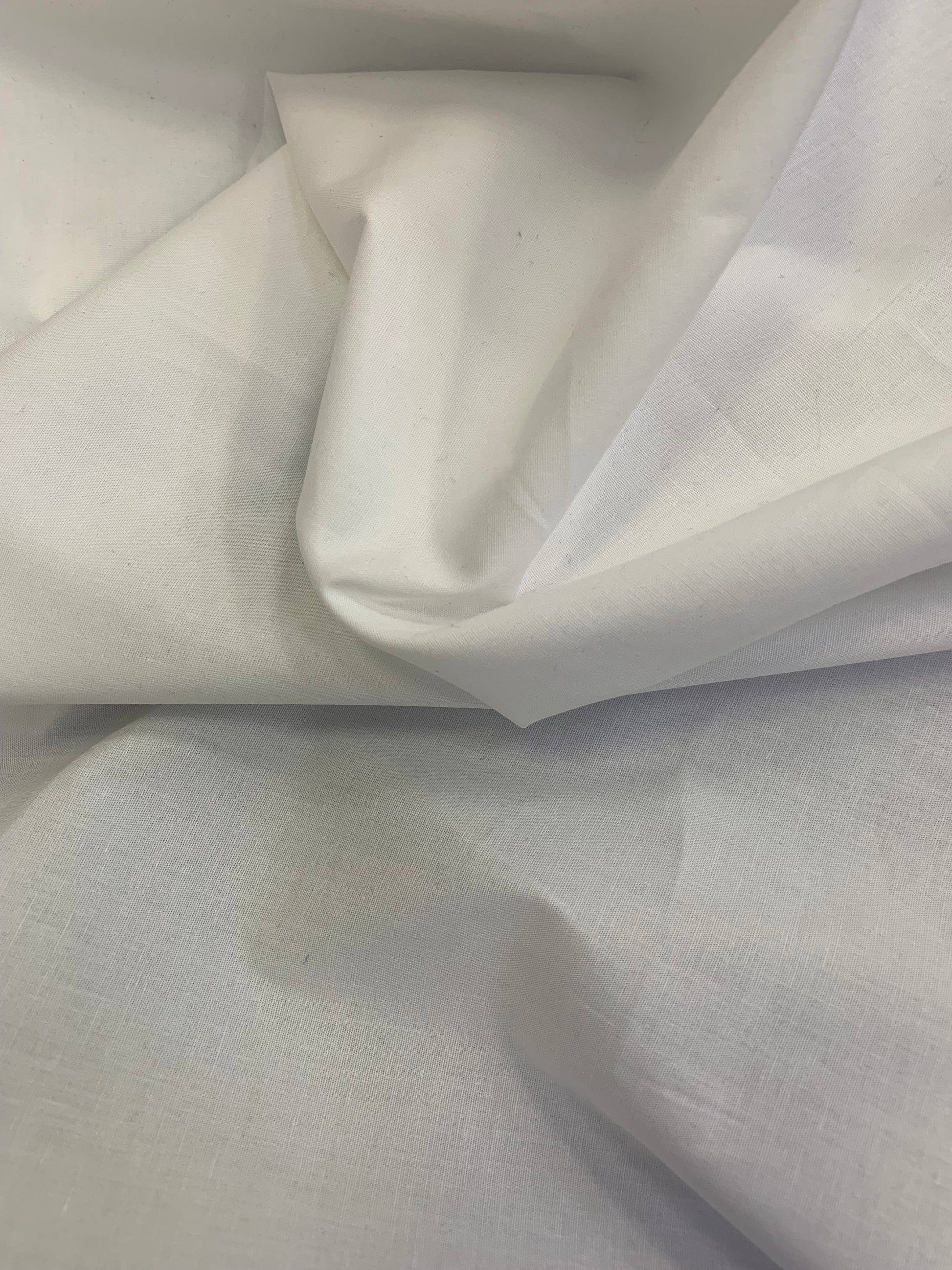 Plain white fabric is shown close-up with soft folds