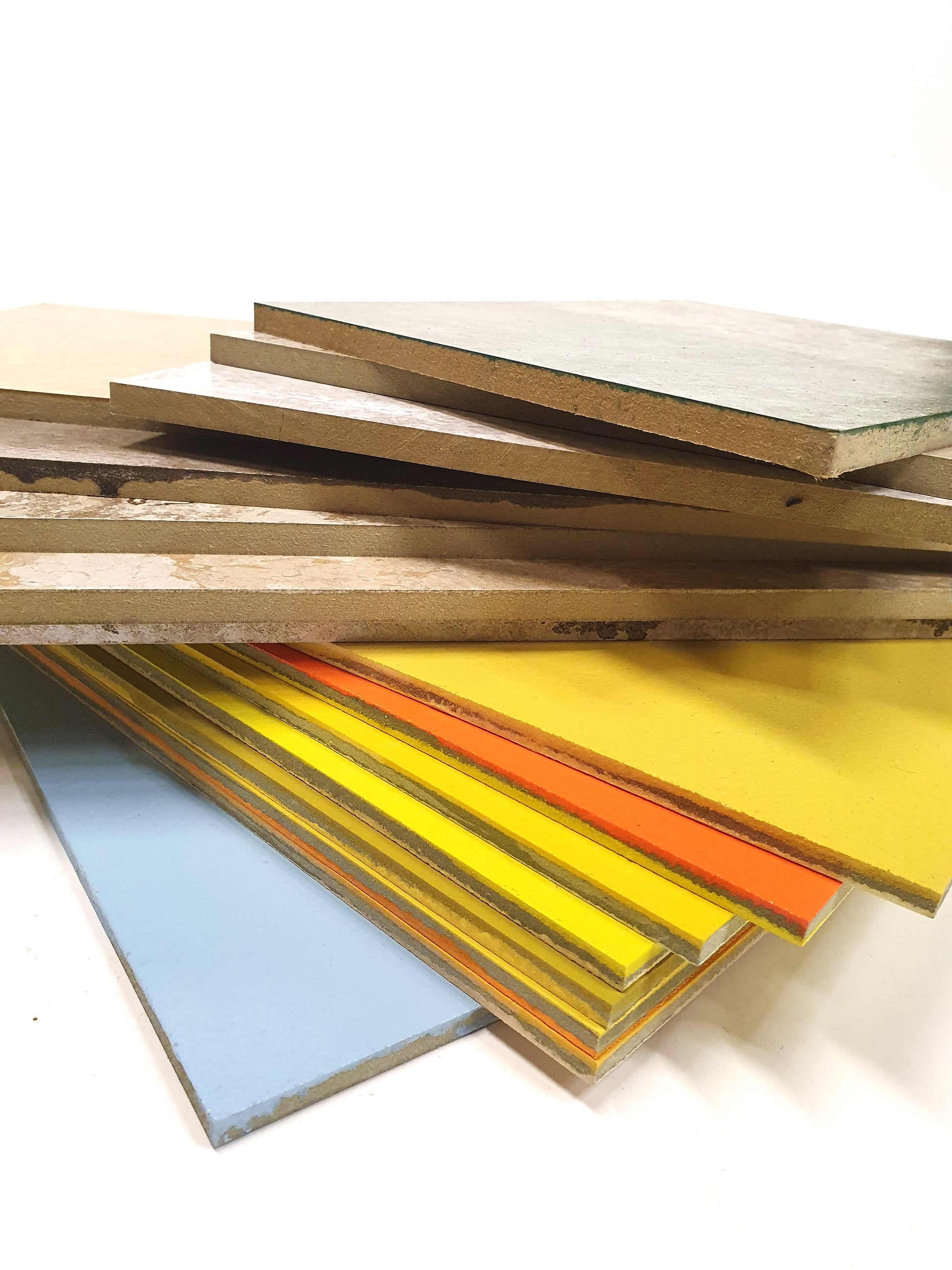 Mixed sample boards are stacked in a layered pile on white