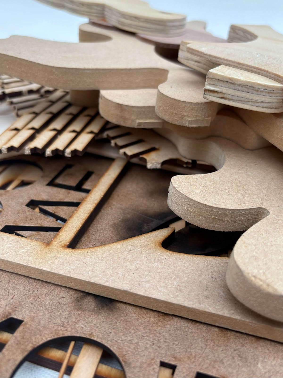 Close-up views show laser-cut wood pieces in different shapes and sizes