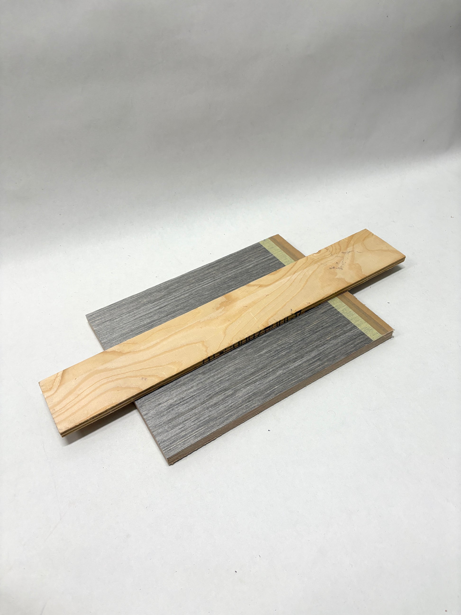 Assorted flat wood pieces are arranged in a stacked pile
