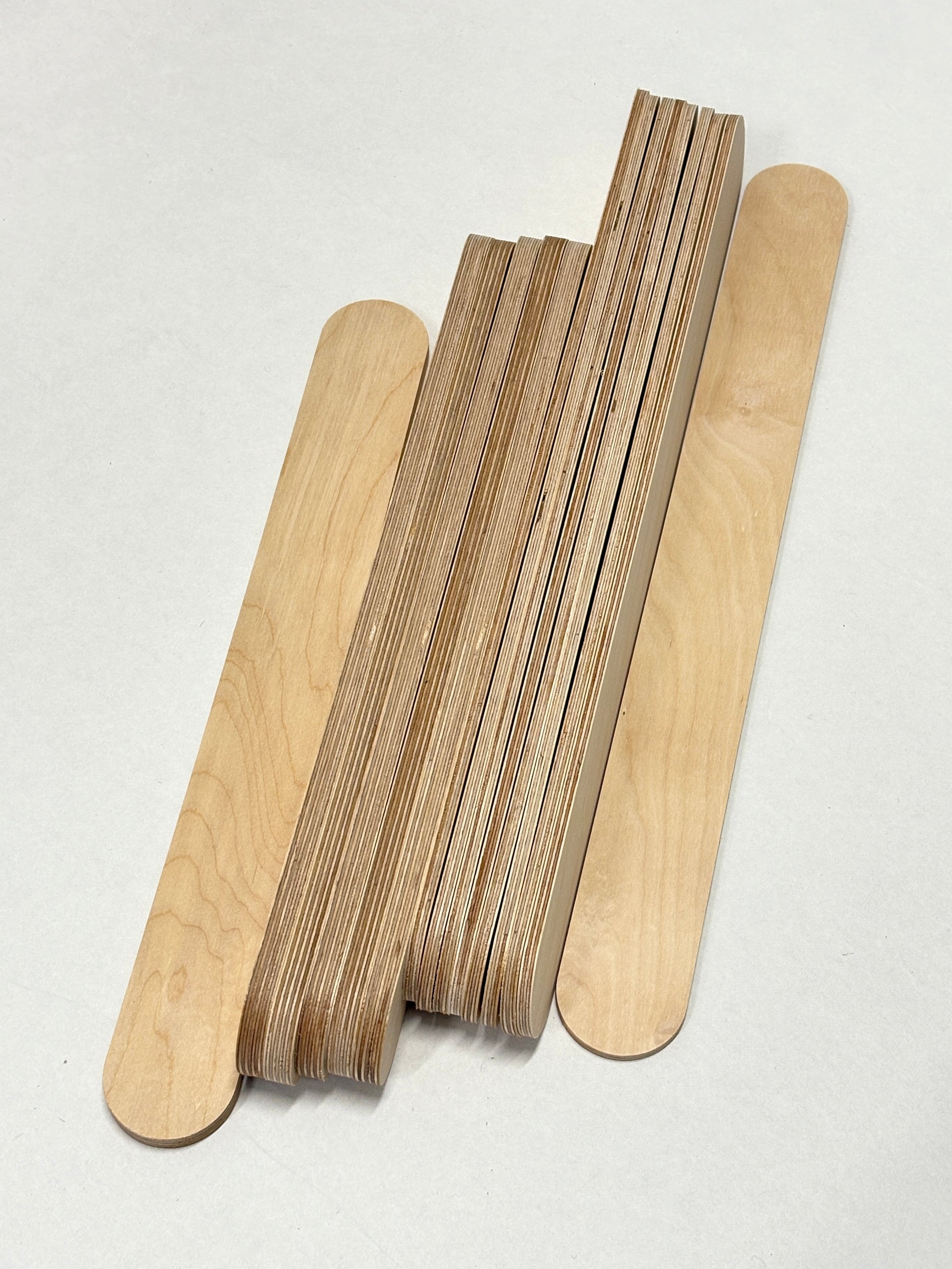 Stacked plywood slats and wooden sticks arranged on a white background.