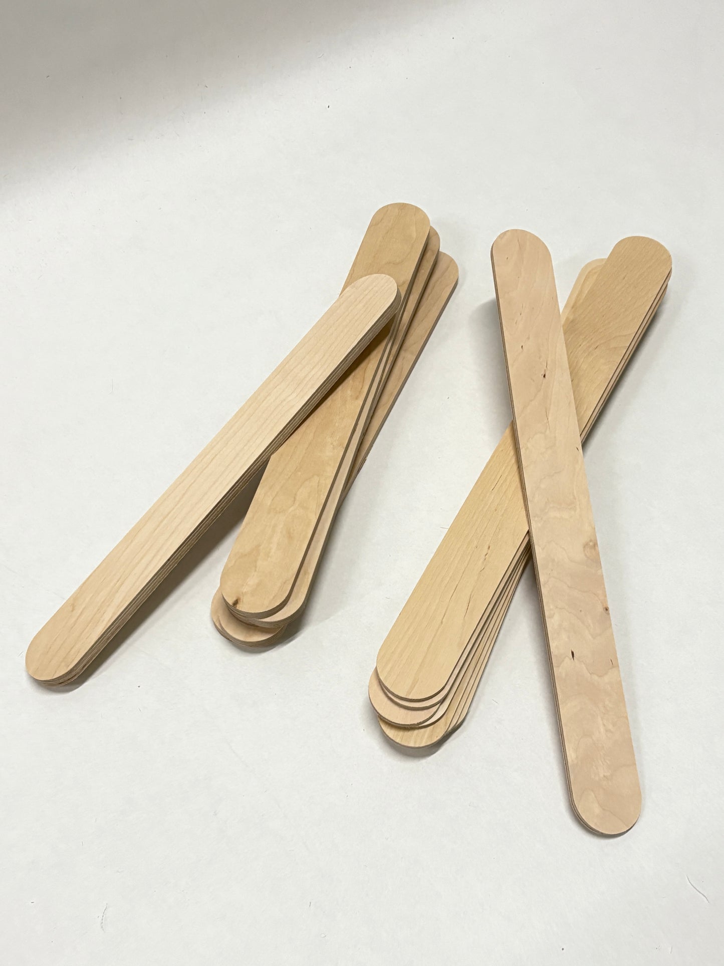 Close-up of plywood strips and rounded wooden sticks on a white background.