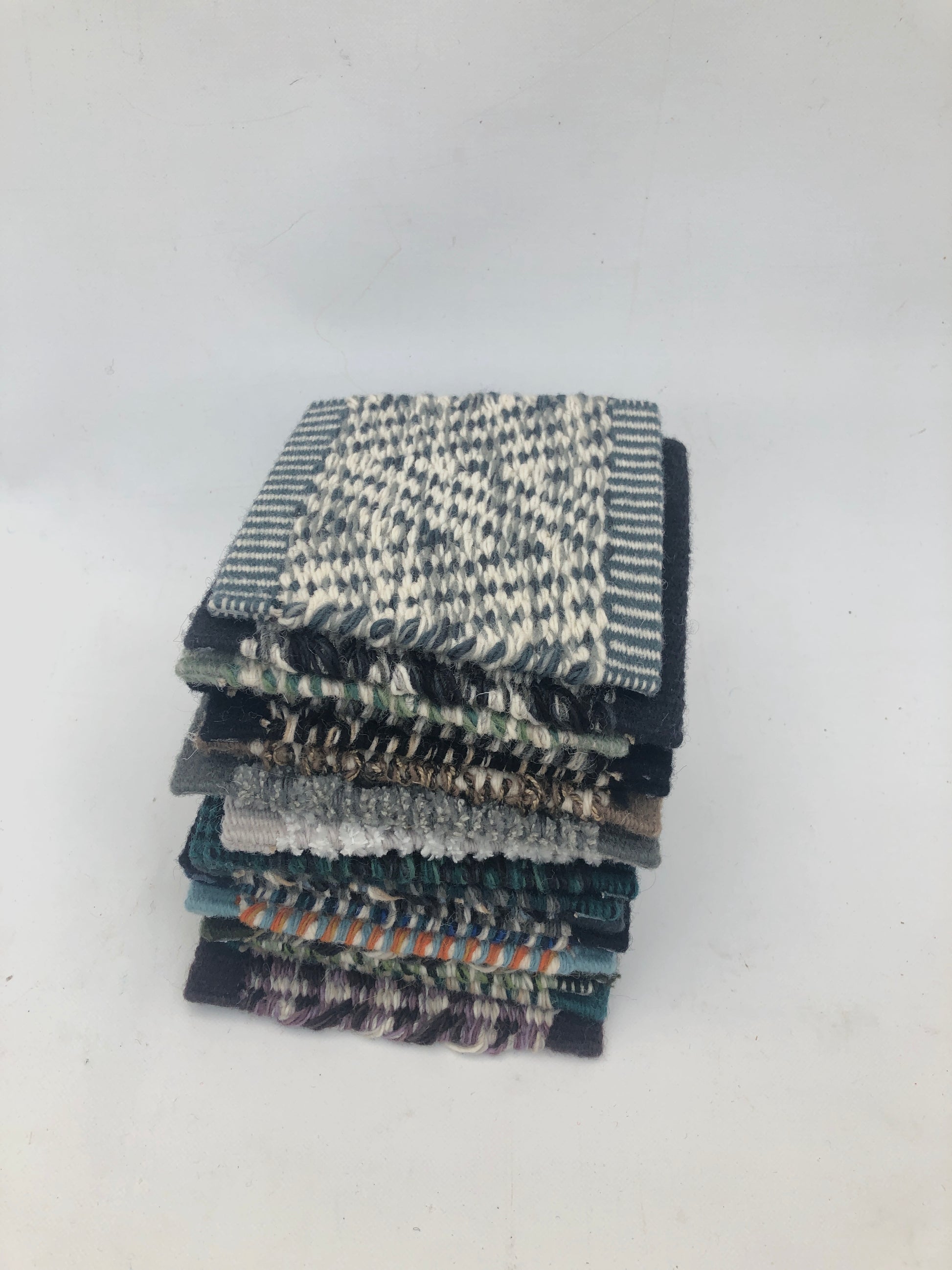 Small textile sample squares are stacked on a white background