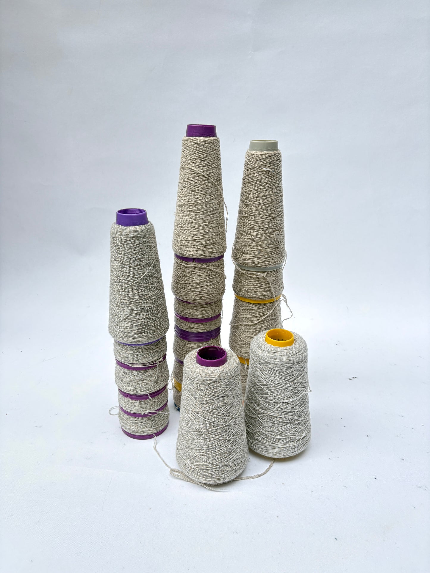 Several cones of off-white thread stand on a white surface