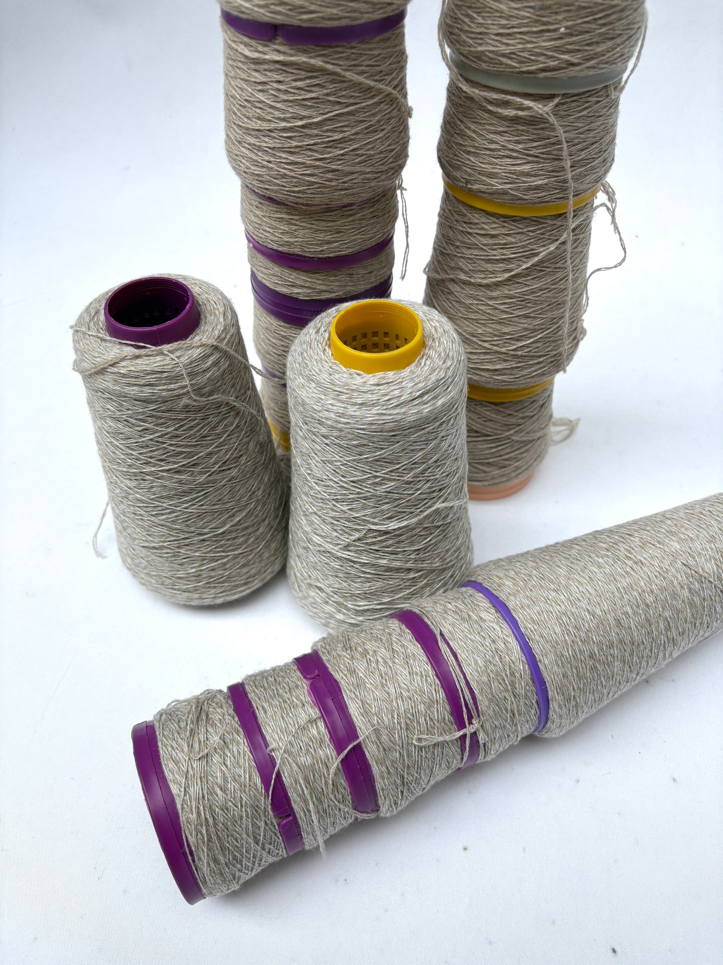 Off-white thread spools are grouped together in upright and horizontal positions