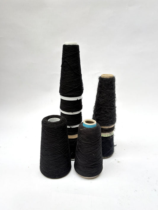 Black thread cones are grouped upright on a white background