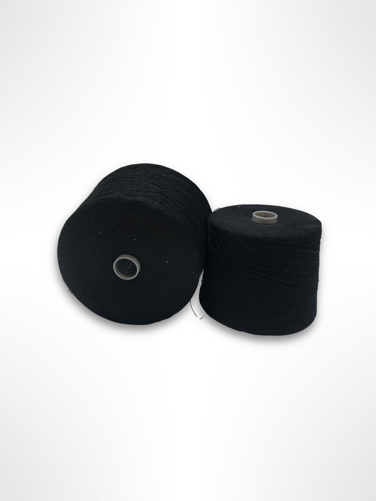 Black thread cones are arranged together on a white surface