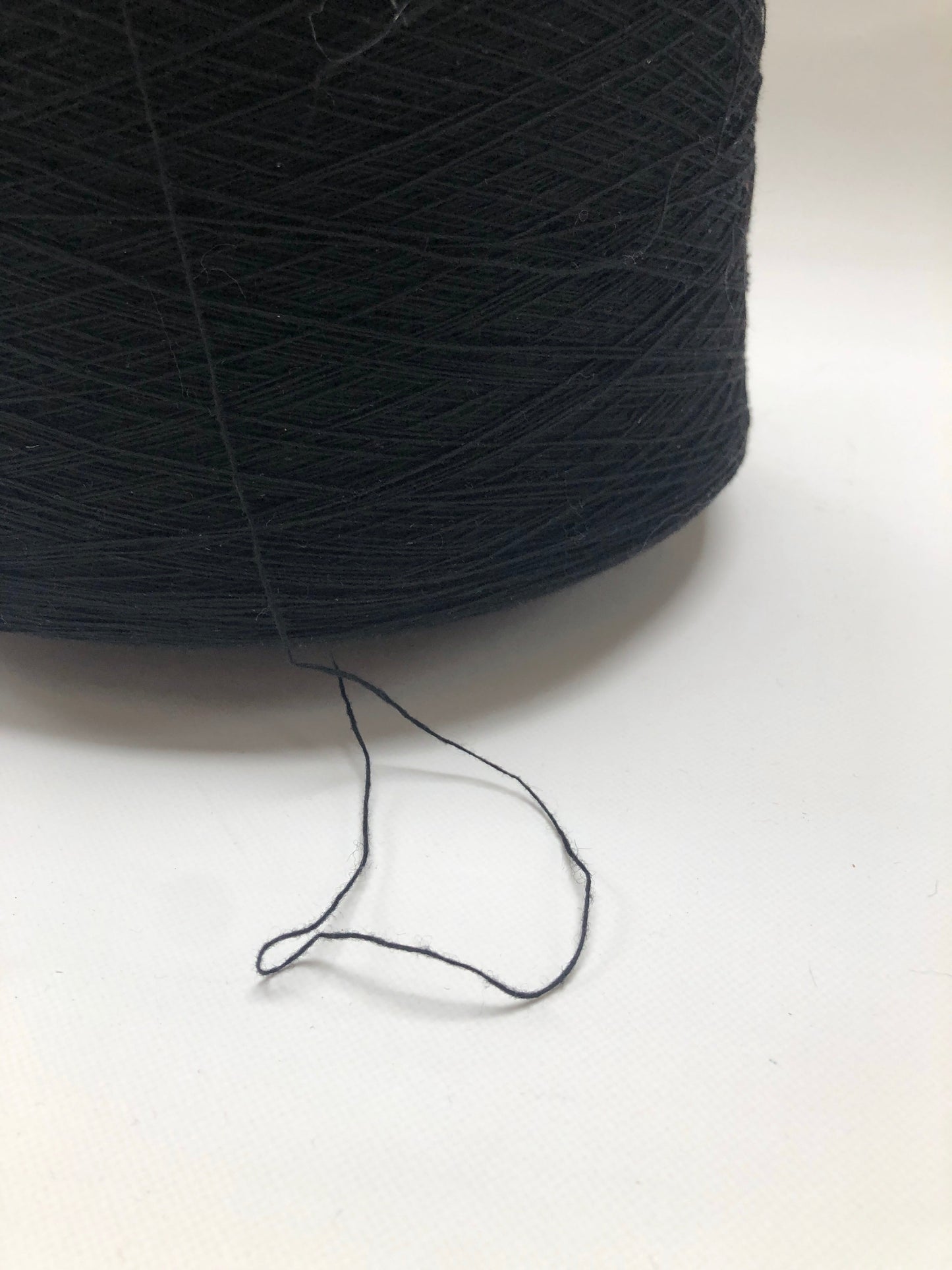 A black thread spool is shown in detail with a loose end