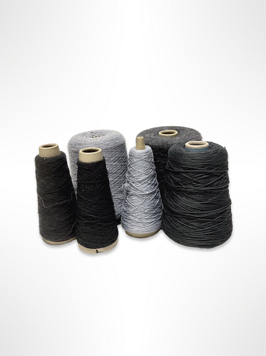 A collection of yarn cones in various shades of grey, displayed on a white background.