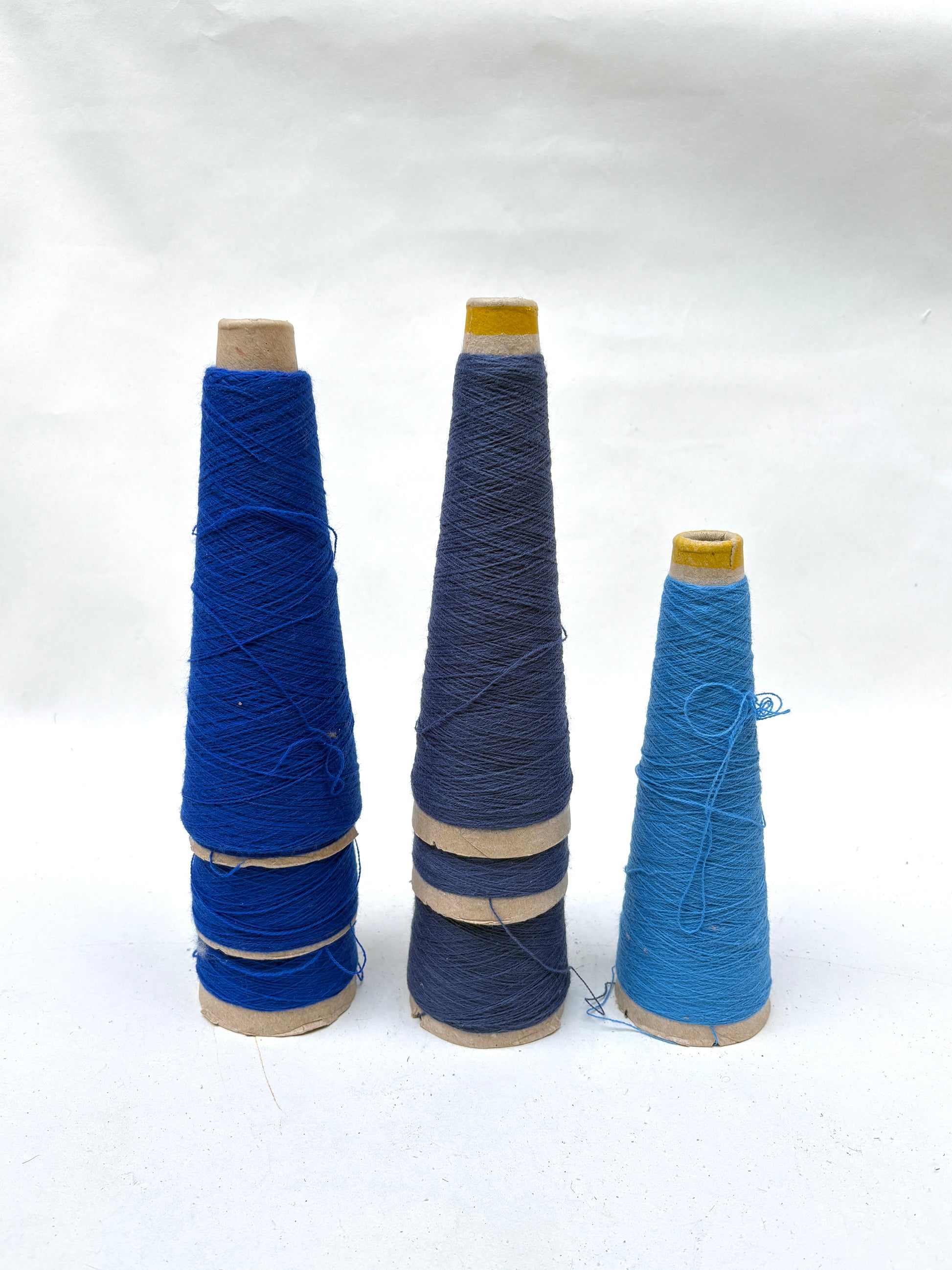 Blue thread cones are grouped together on a white background