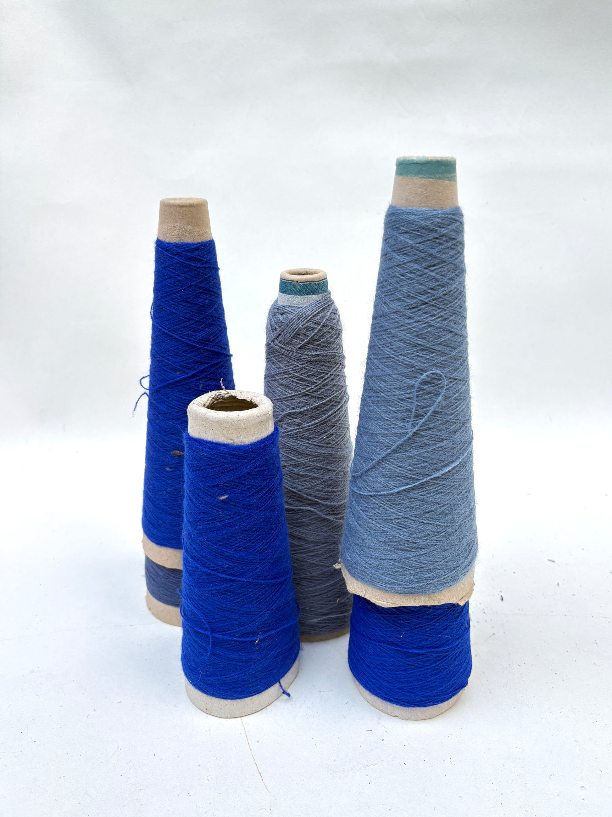 Thread spools in light and dark blue are arranged upright