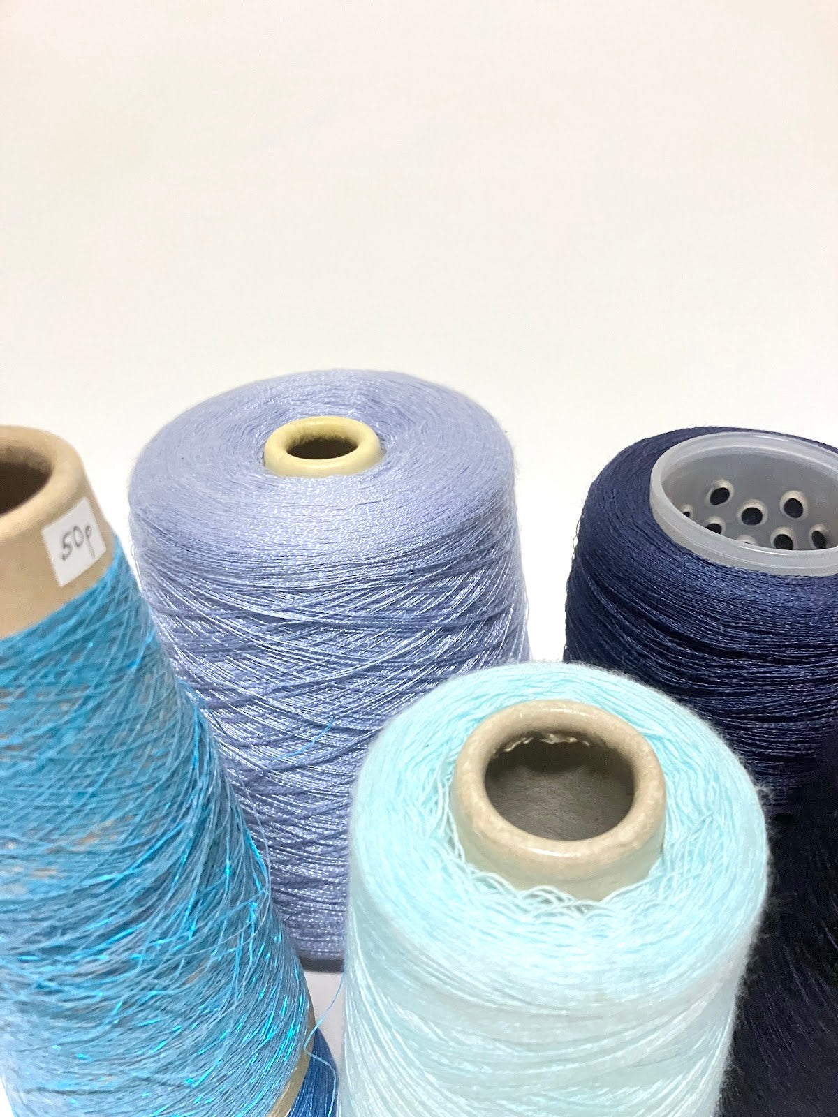 Blue and turquoise thread spools are displayed in a small group