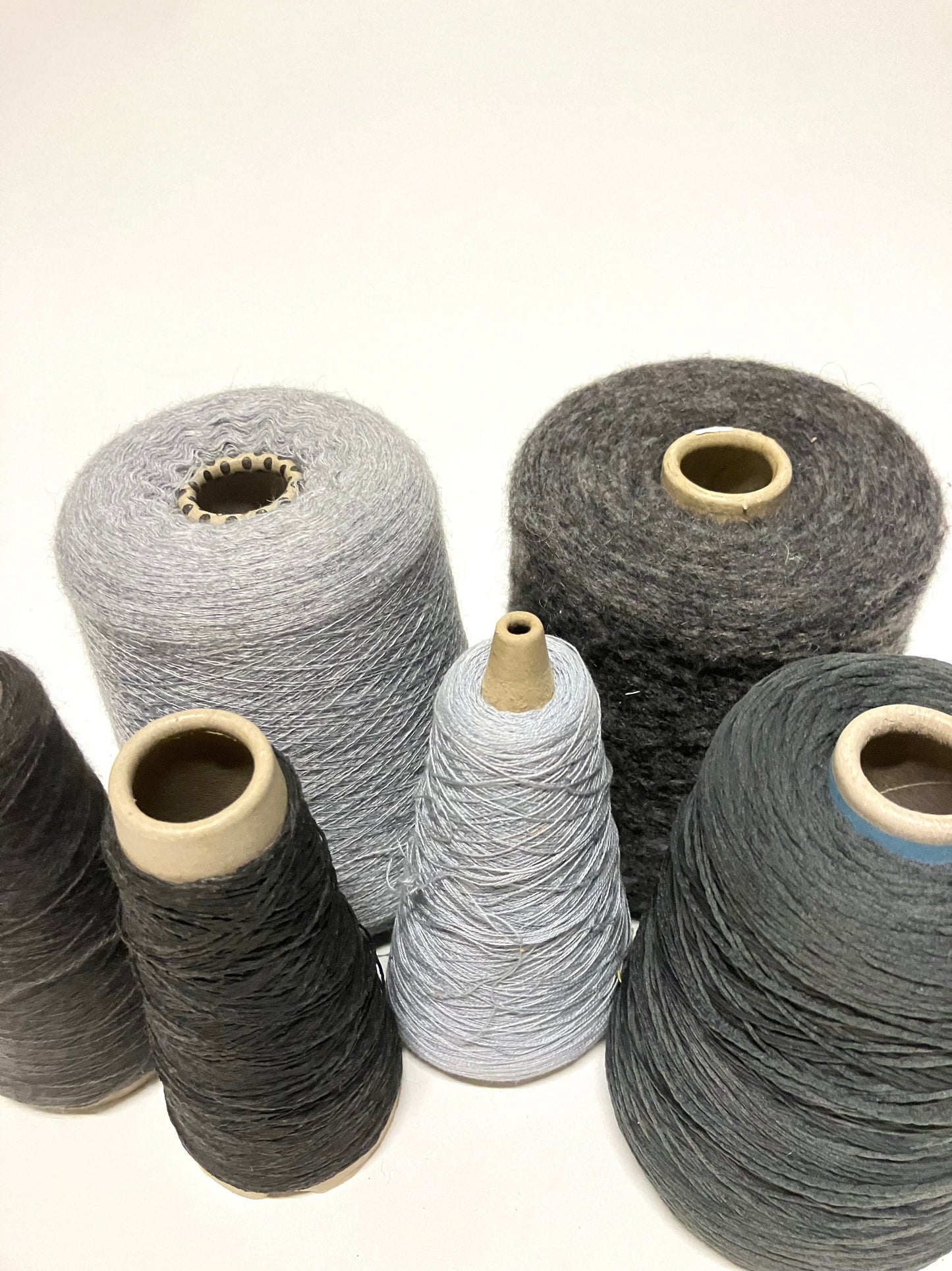 grey  thread cones are grouped together on a white background