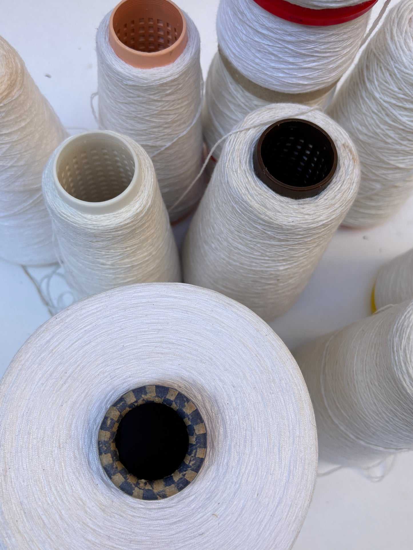 White shade yarn cones from a mixed bundle arranged together on white.