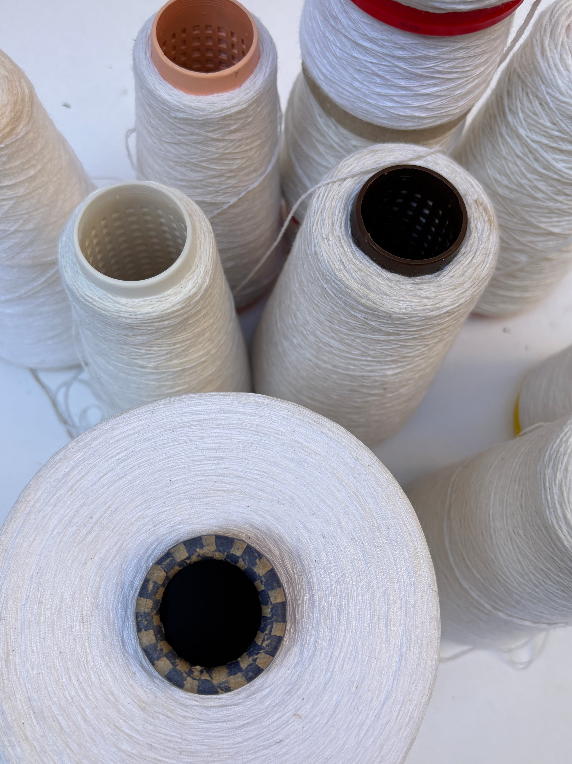 White shade yarn cones from a mixed bundle arranged together on white.