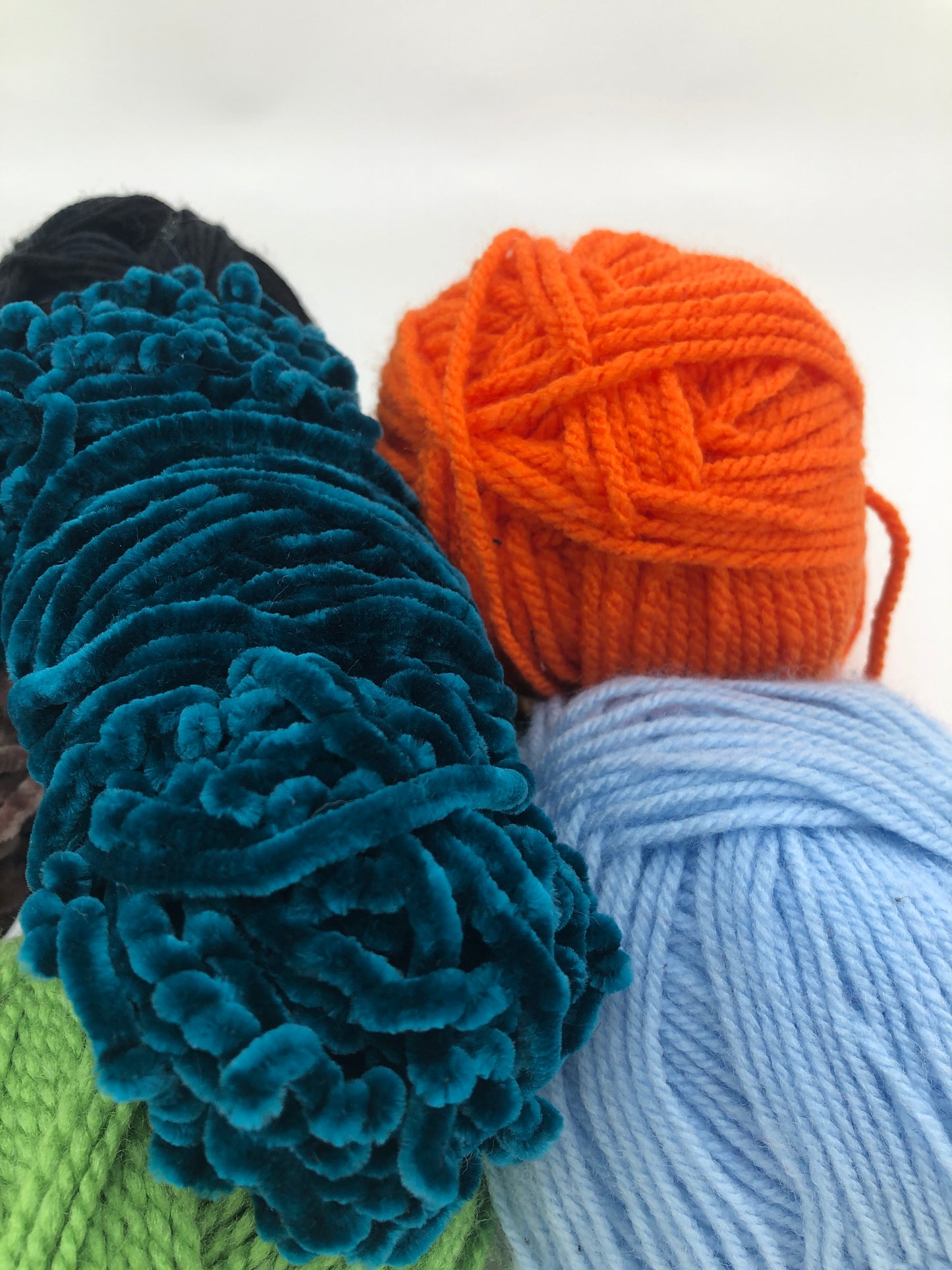 orange and blue yarn balls are displayed together on a white surface