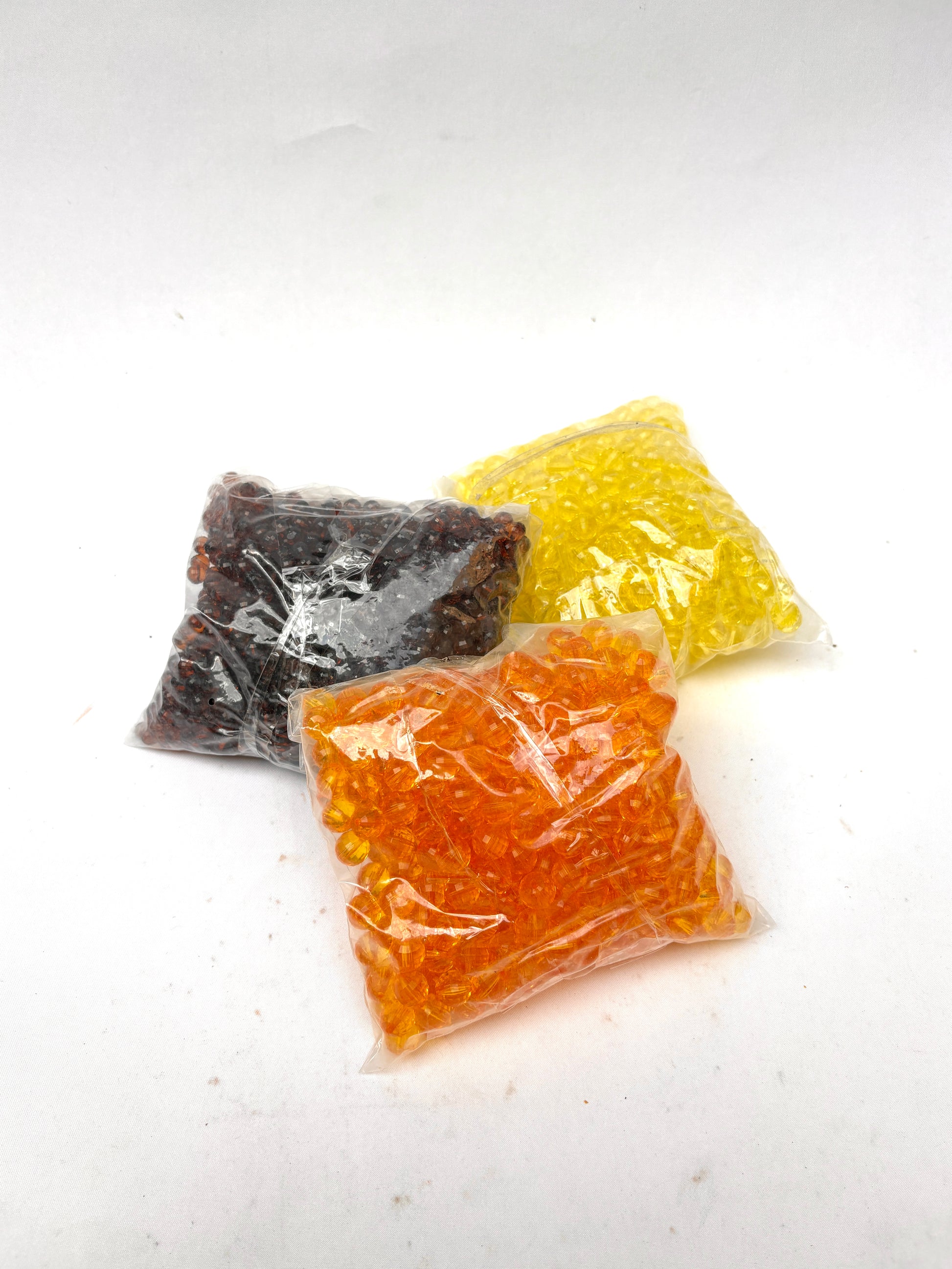 Three bags of coloured acrylic beads, in amber, yellow, and brown